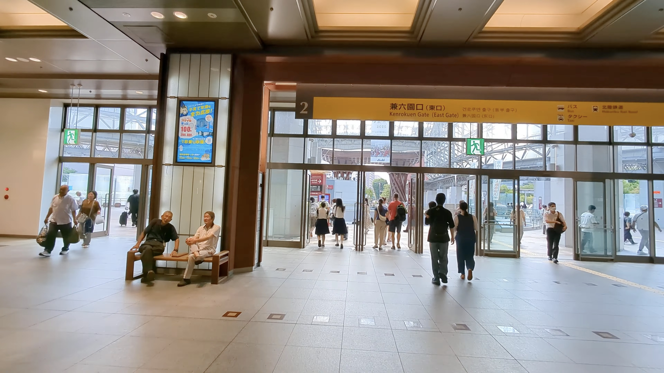 改札内から兼六園口（東口）へ、ガラス越しに鼓門の赤い柱