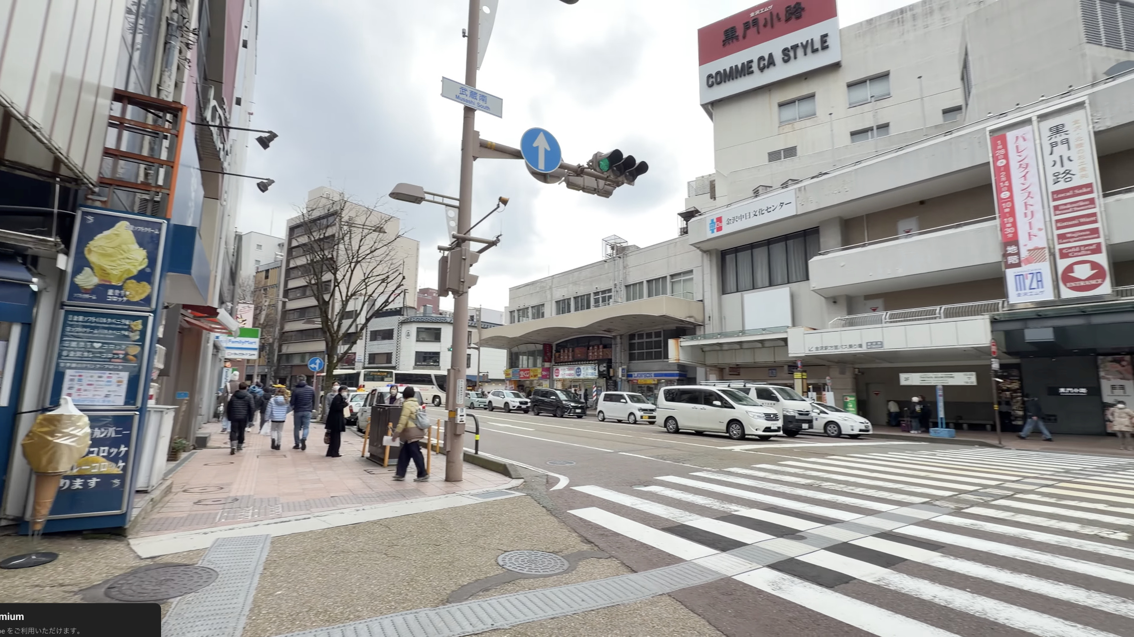 「エムザ口」前の交差点、正面に金沢エムザと「黒門小路」の看板、横断歩道を渡る人たち