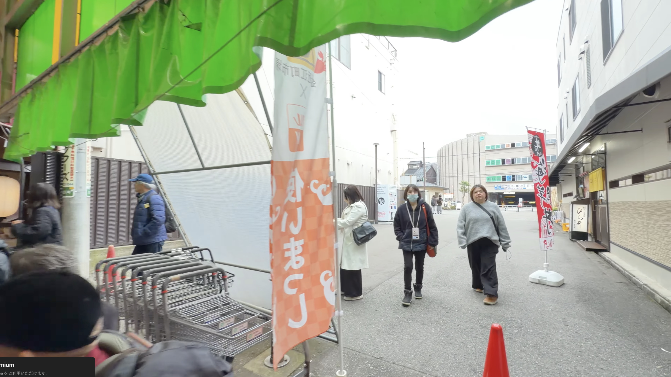 市場の路地に立つ「使いまっし」ののぼり旗、奥に交差点と金沢中日文化センターの建物
