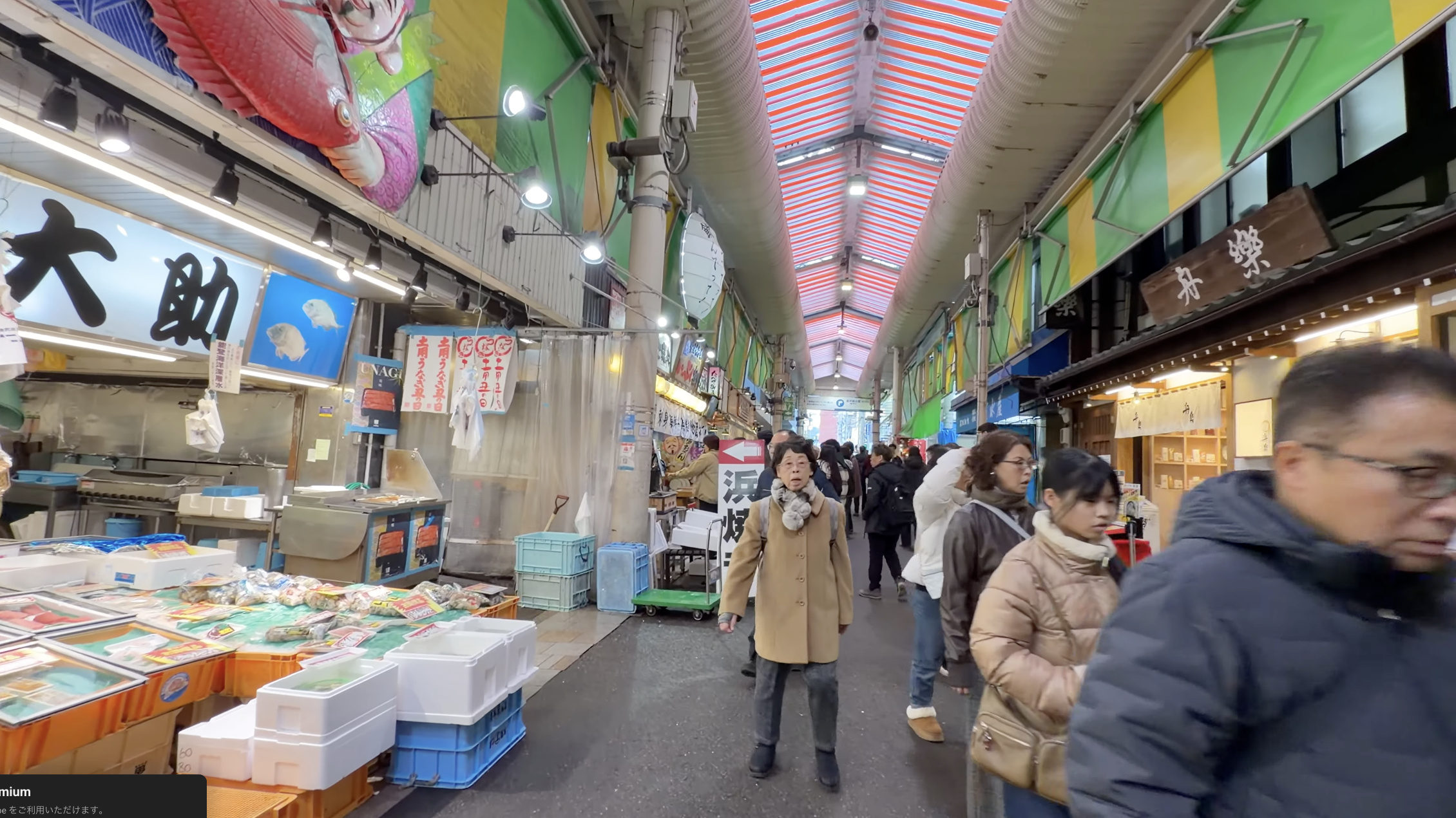鮮魚店「大助」の店先、水槽の魚のイラストと、通りを歩く大勢の買い物客