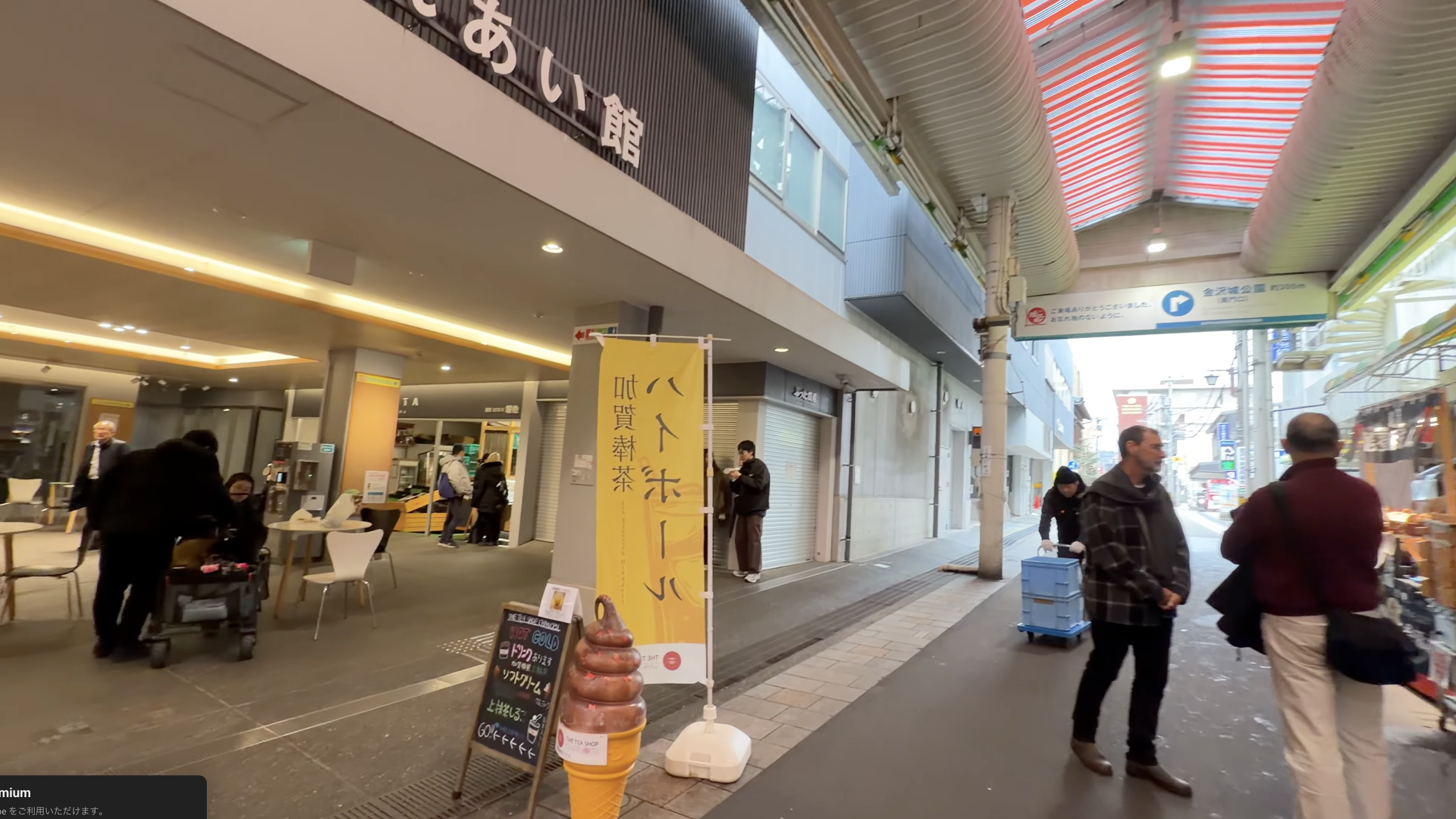 黄色い「ハトホール」ののぼり旗と「叺賀鮮茶」の看板、近江町いちば館の建物前の通り