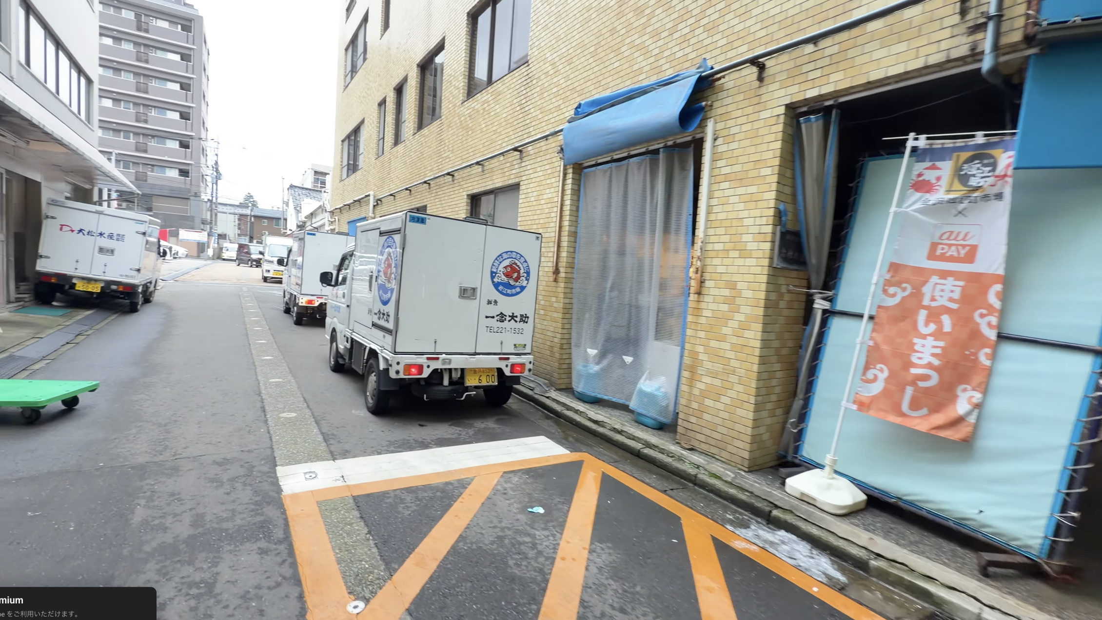 市場の裏通りに並ぶ配送用の軽トラック、車体に「一念大助」の文字
