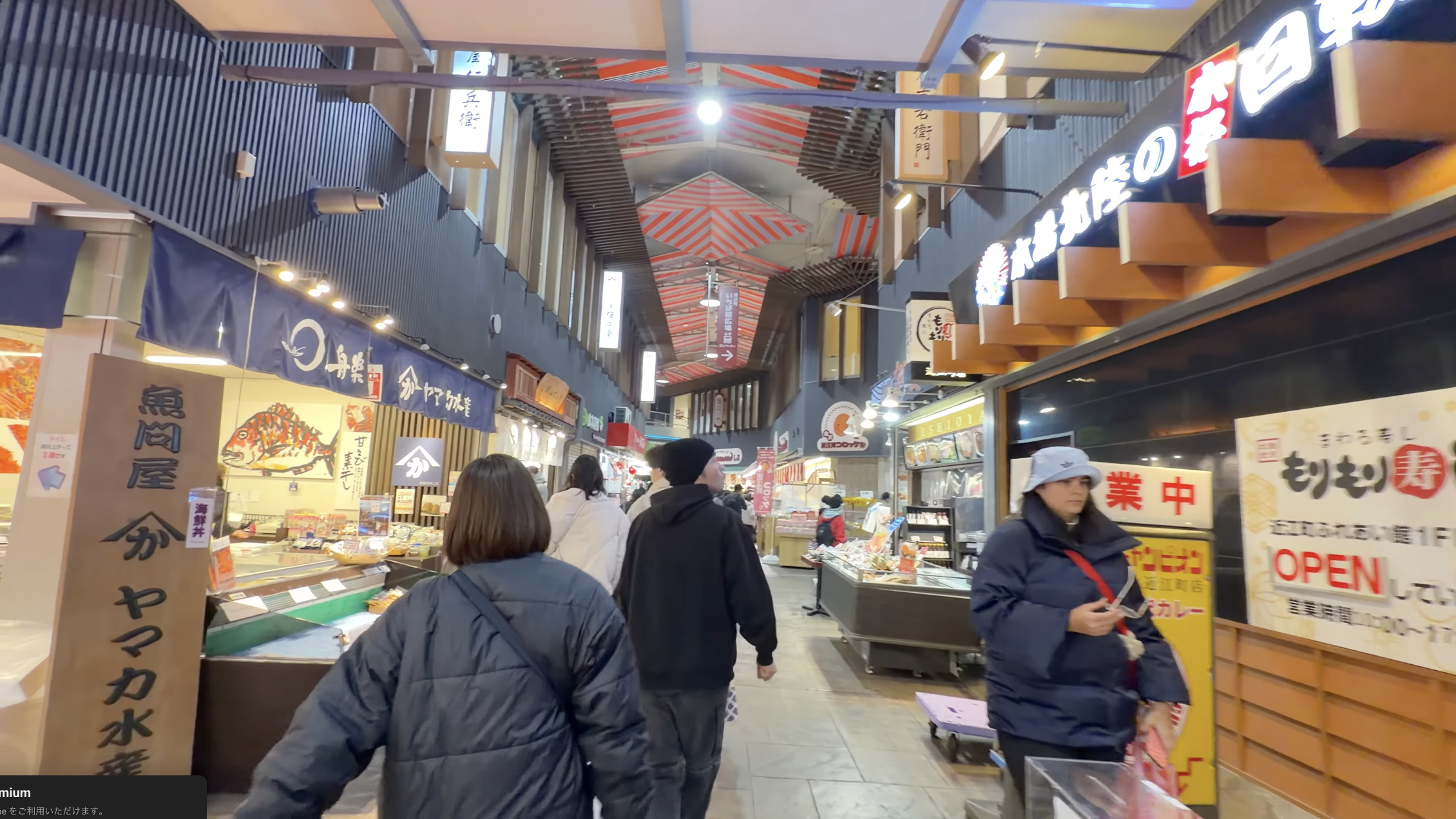 「屋兵衛」の看板が掛かる、近江町市場の小さな路地。奥に赤い提灯とテントの色