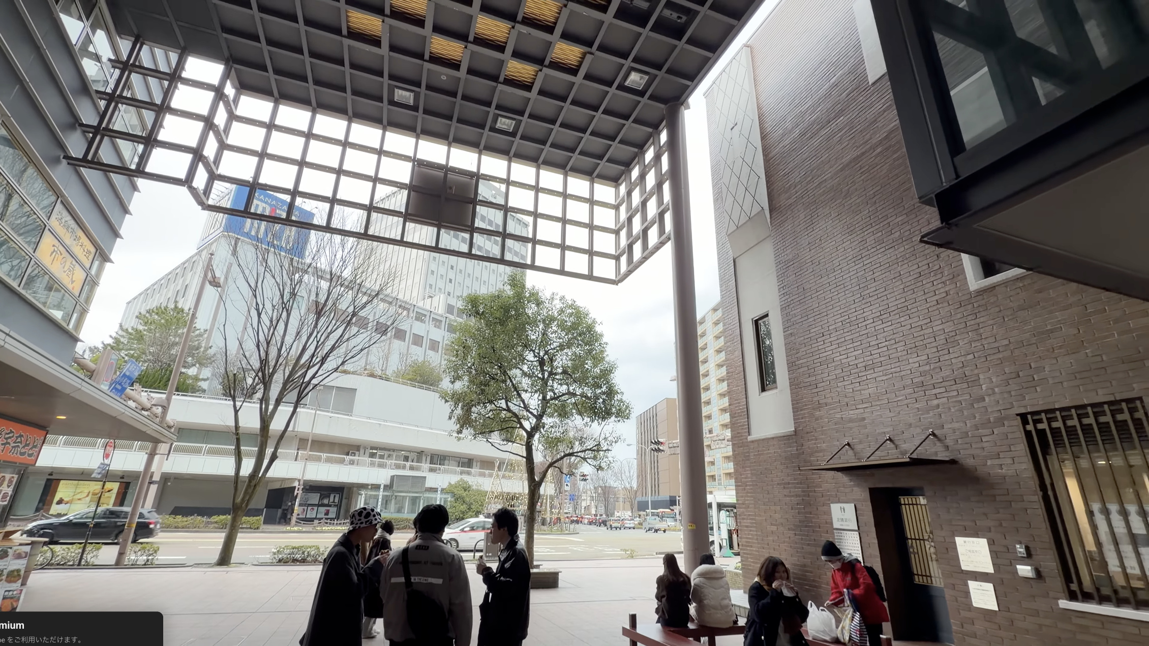 近江町いちば館の広場、格子状の天井の下でベンチに座る人たち、奥に金沢の街並み