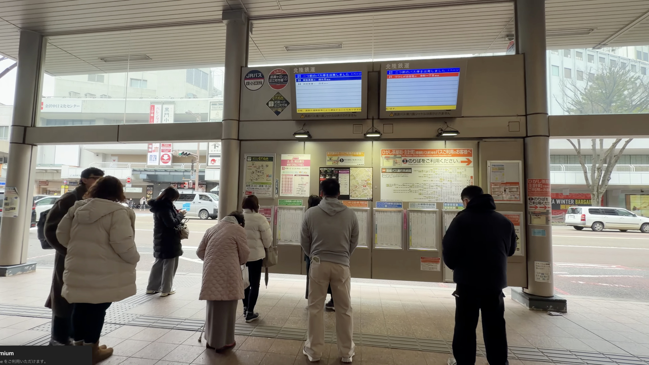 エムザ口前のバスのりば、北陸鉄道の運行情報モニターの前でバスを待つ人たち