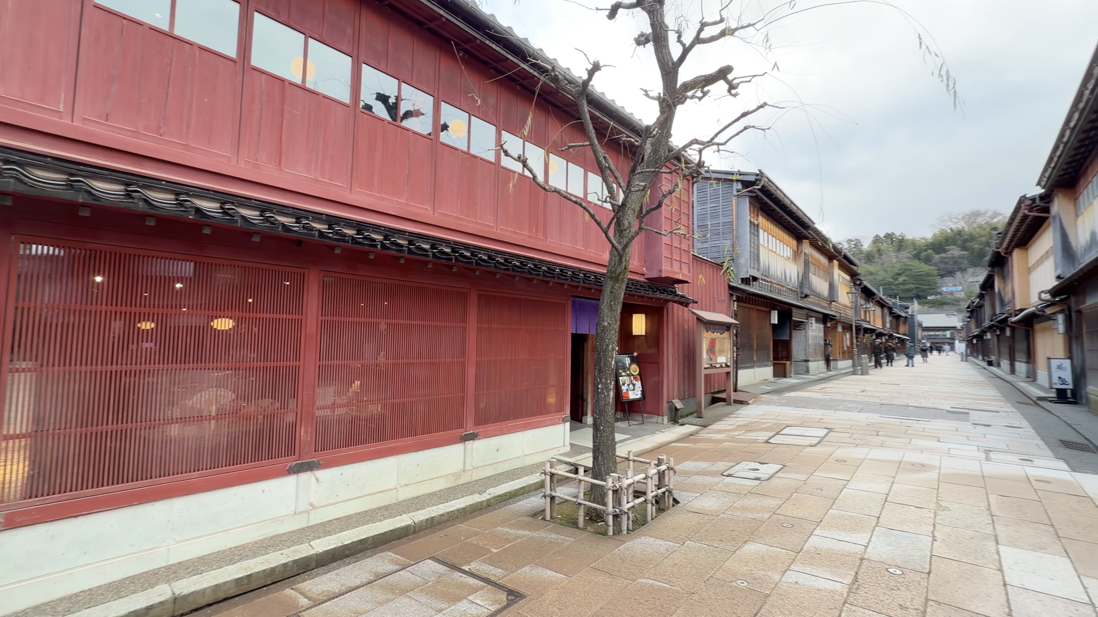 開店前のひがし茶屋街メイン通り、赤い格子戸の茶屋建築と裸木、静かな石畳の通り