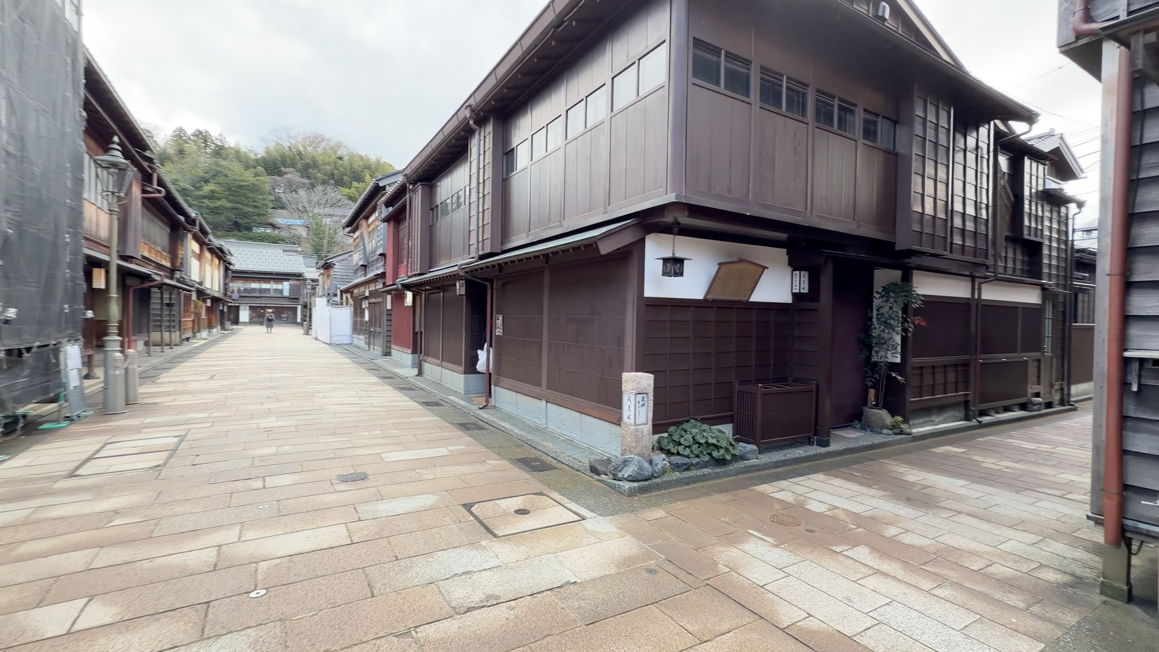 ひがし茶屋街の角地に建つ茶色の木造建築、石柱と植木鉢のある店先