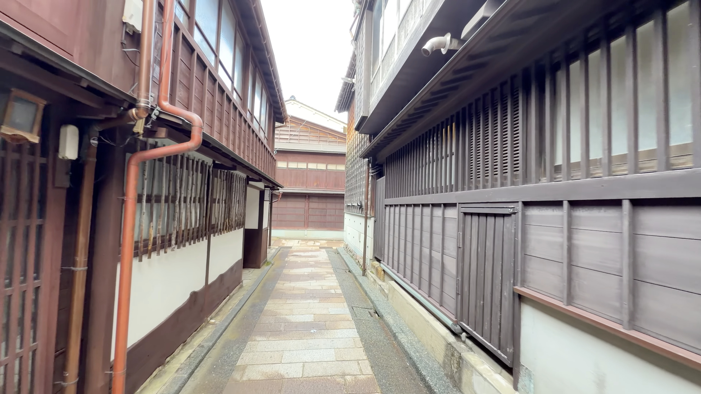 電線の張る狭い路地の奥、木造家屋が両側に連なる様子