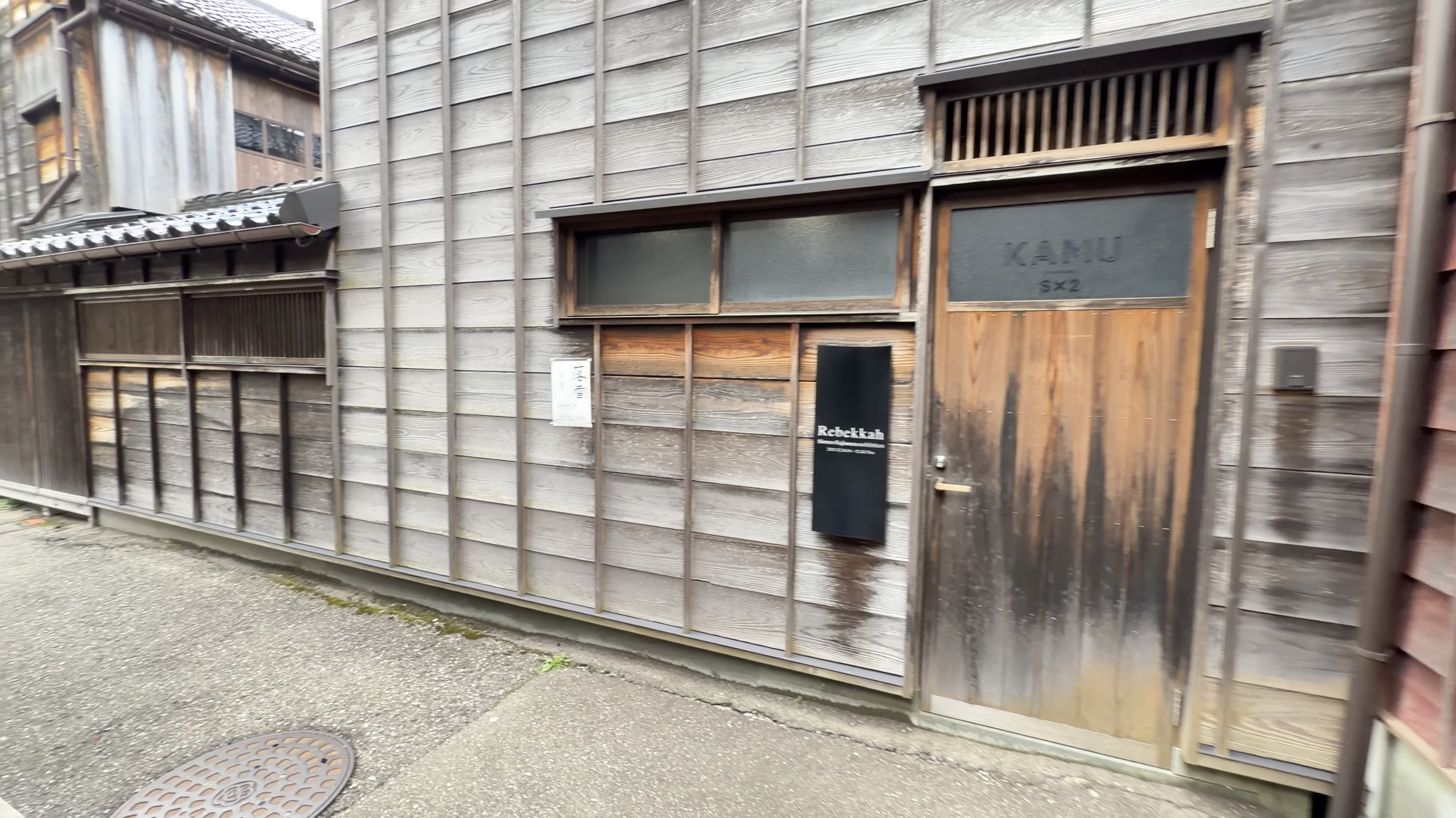 改装された茶屋建築の店先、木の壁と暖簾、店名の看板が掛かる通り角