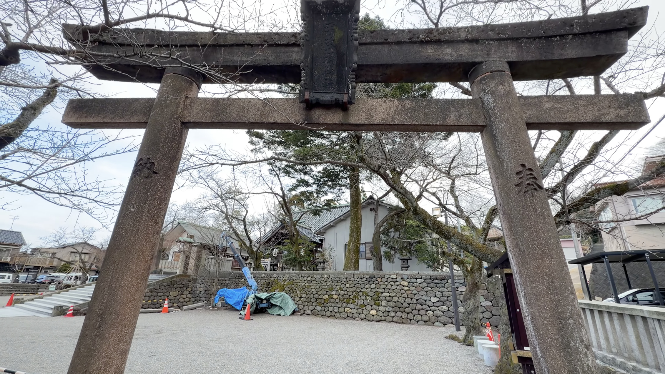 宇多須神社の石鳥居のクローズアップ、奥に社殿と裸木、砂利の境内