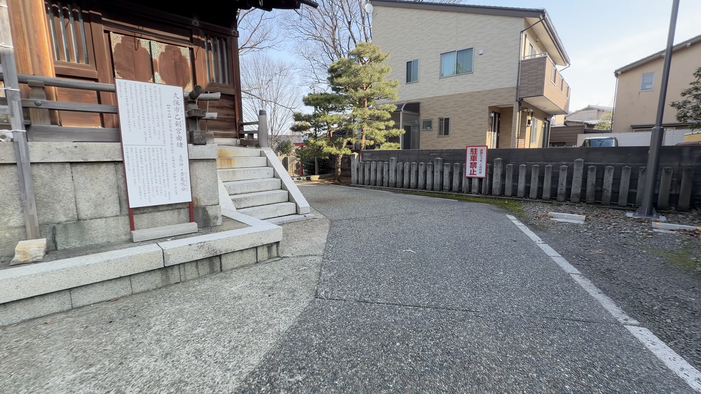 久保市乙剣宮の由緒書きの看板と、朱塗りの社殿、石段の脇に立つ松の木