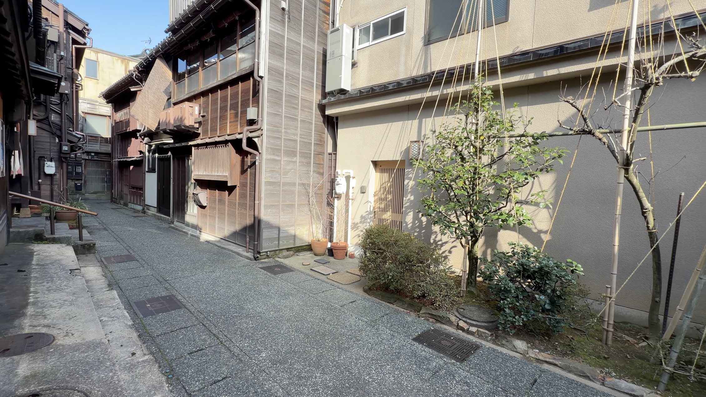 主計町茶屋街の狭い通り、木造の茶屋建築が両側に並び、奥に人が数人歩いている
