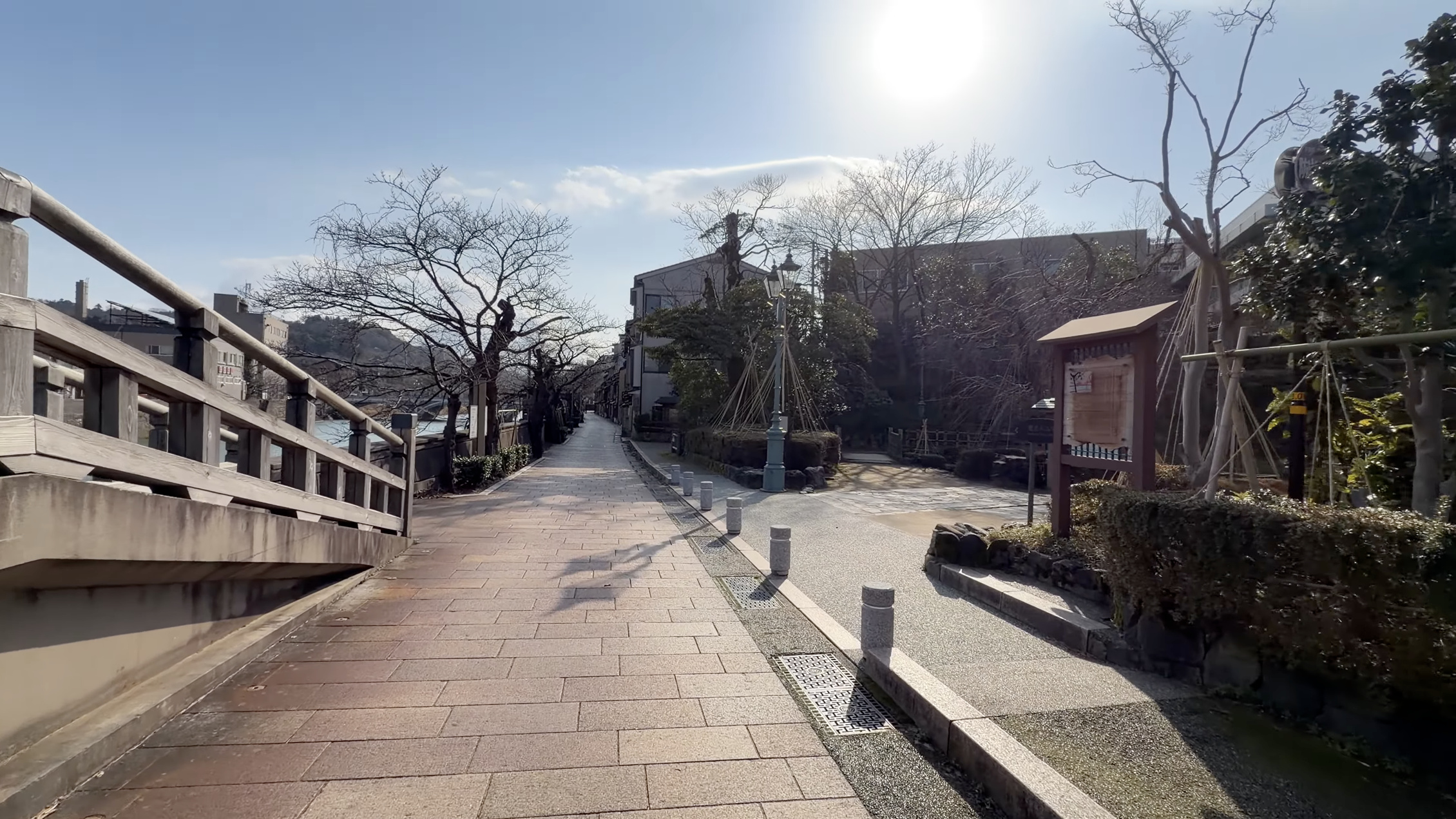 浅野川沿いの遊歩道、案内看板と街灯、奥に中の橋が架かる