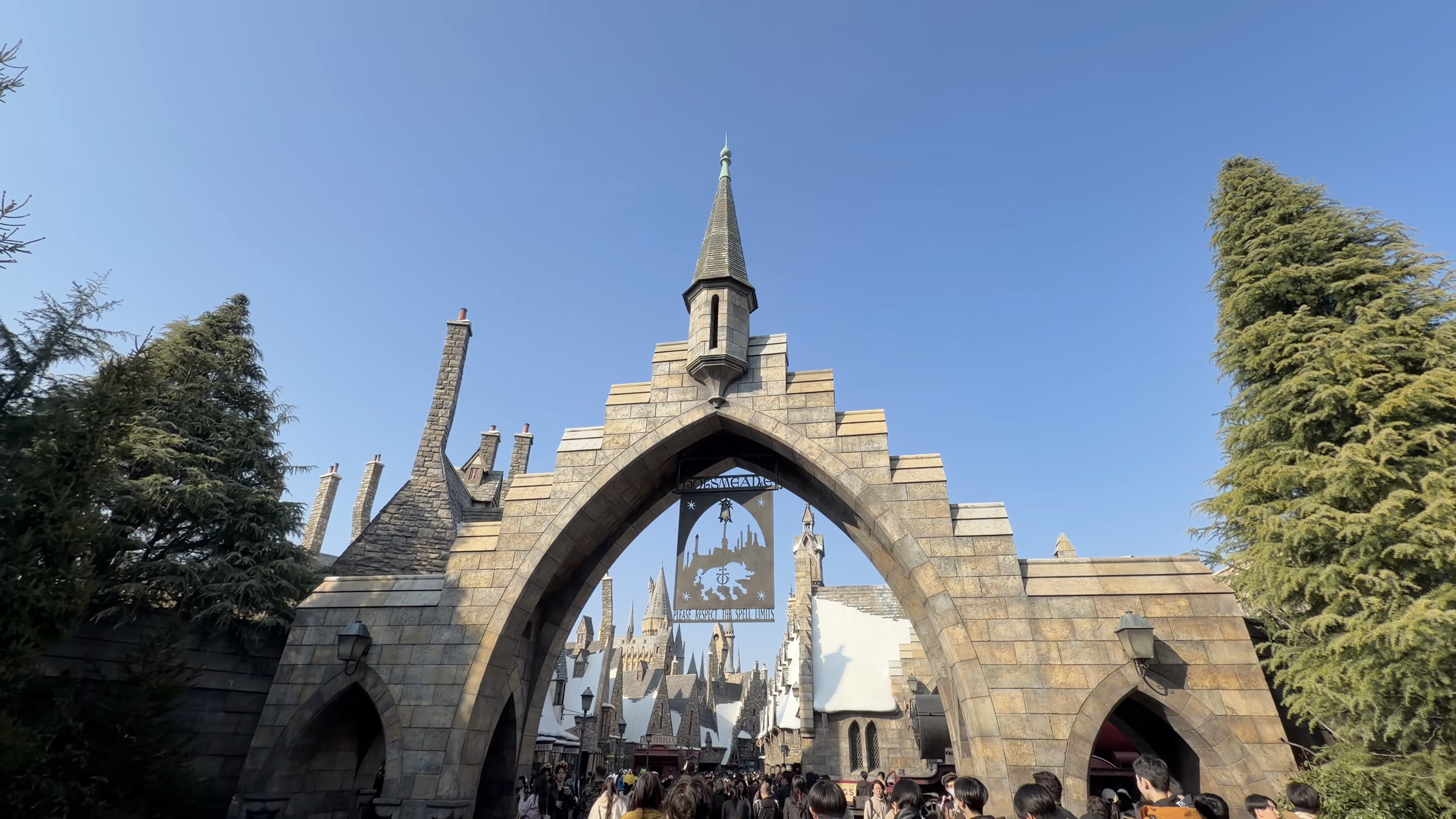 ホグズミード村の入口アーチ。『HOGSMEADE』の看板と、奥にホグワーツ城の尖塔