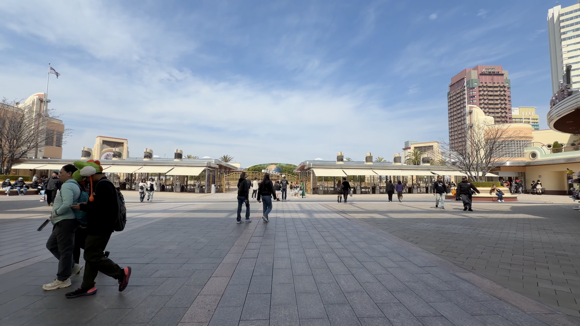 入口前の広場、遠くにゲート越しの地球儀とバナーのアーチ、手前はほぼ無人