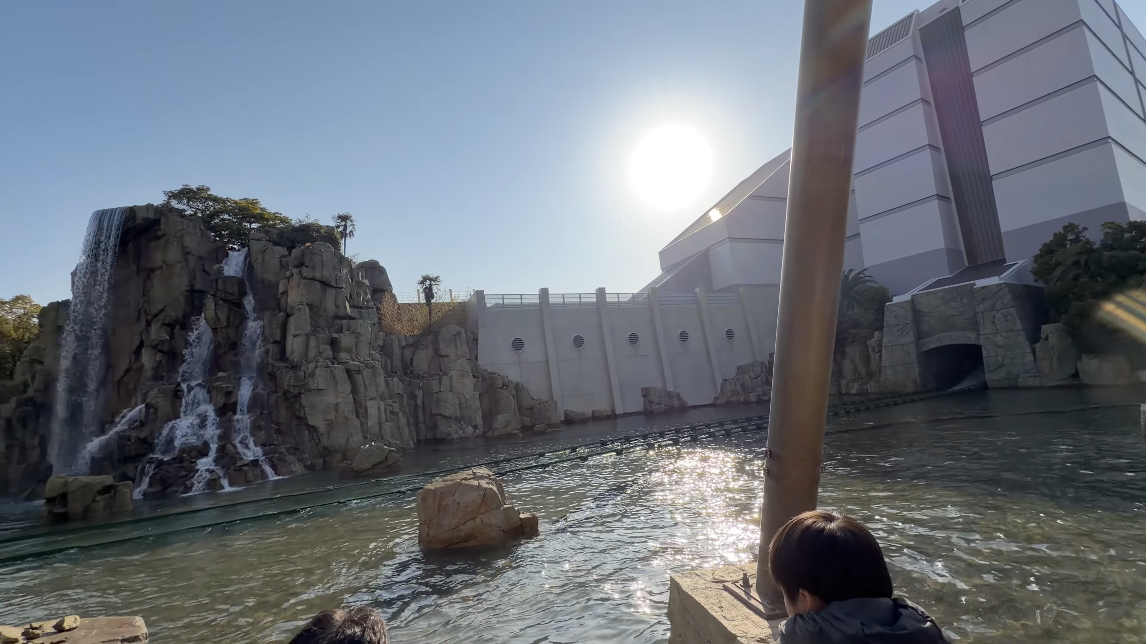 ラグーン沿いの滝と岩山、奥に白い建物