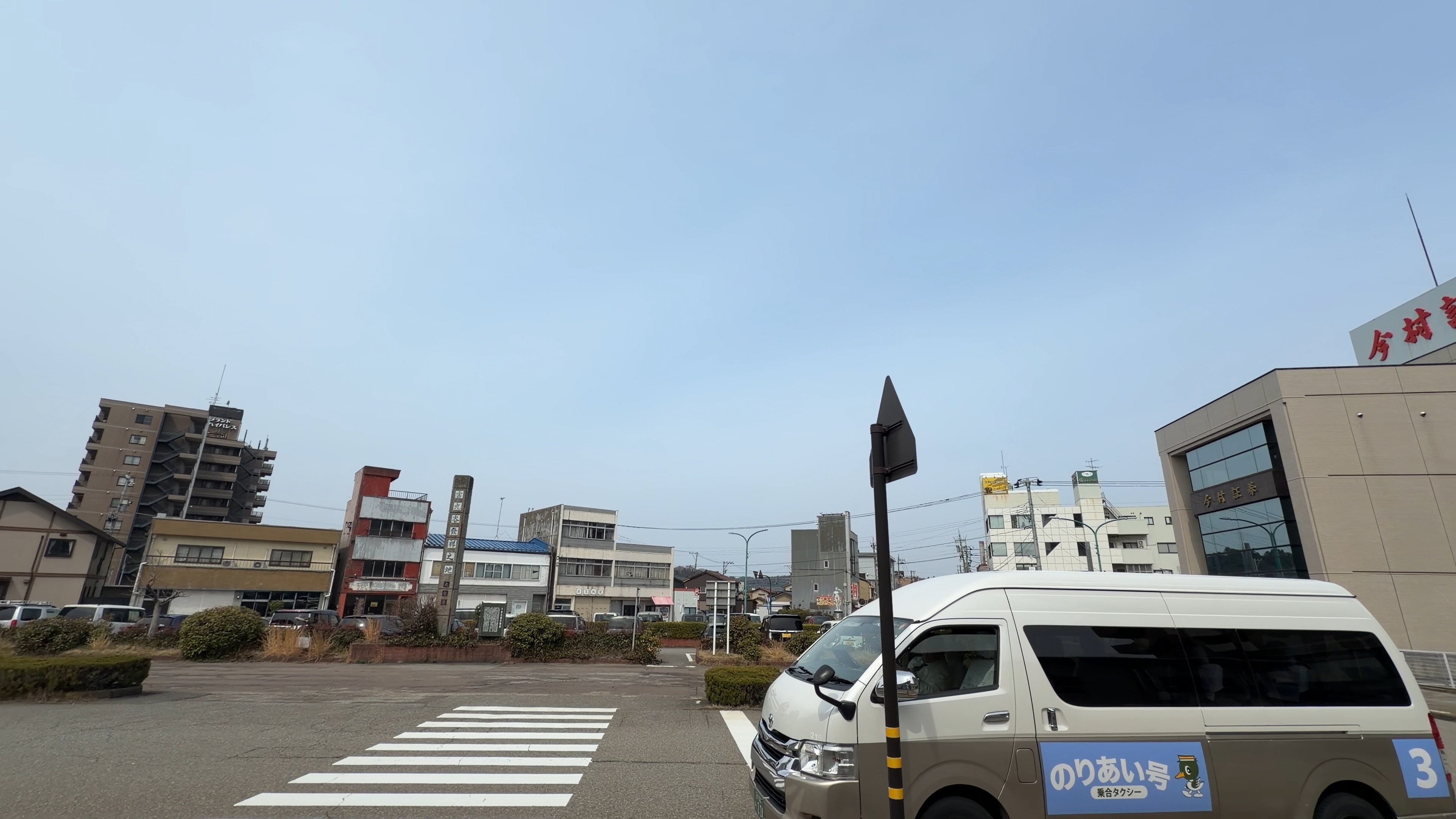 大聖寺駅前ロータリーに停まる乗合タクシー「のりあい号」、奥に古い商店の建物