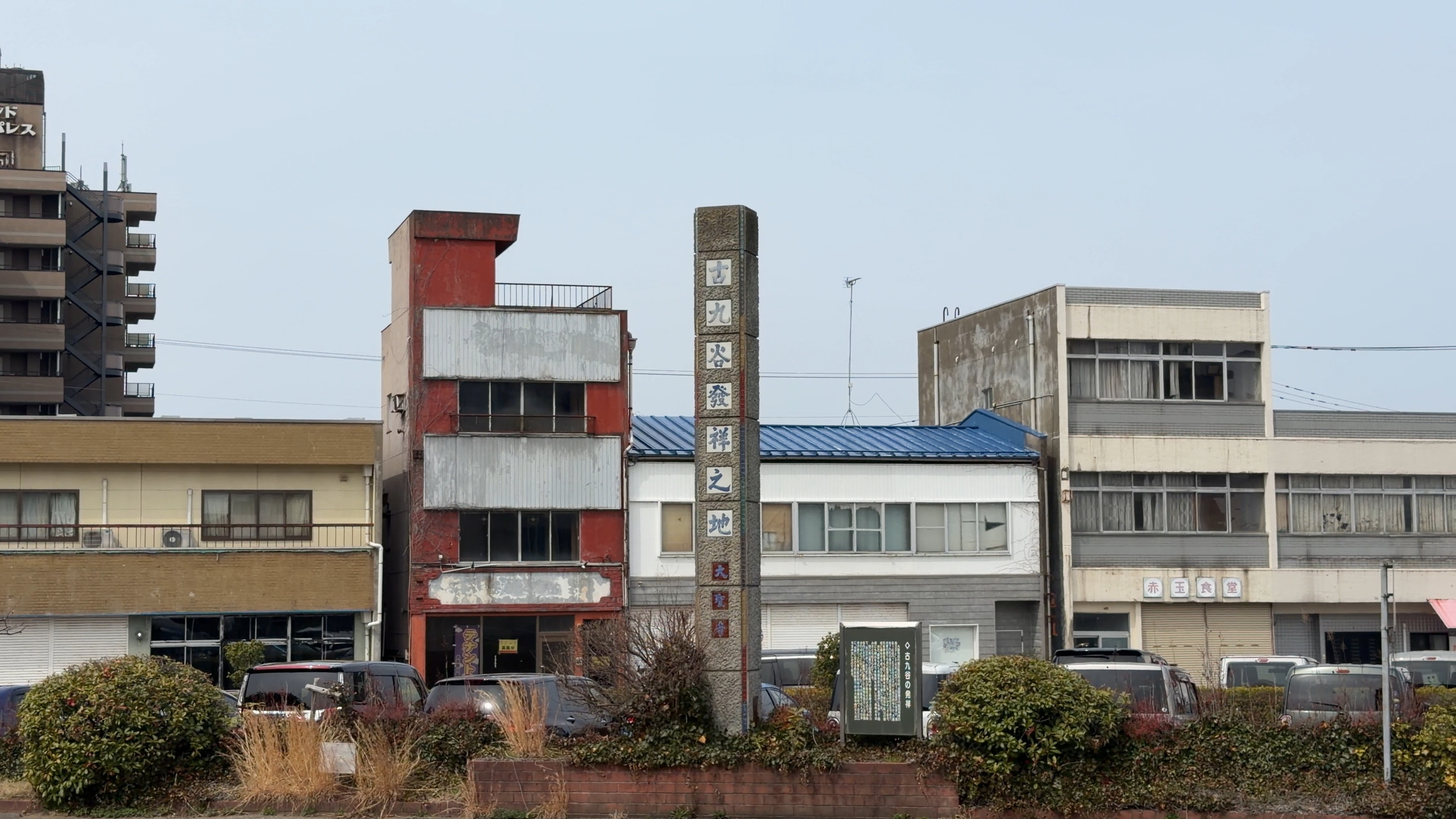 「古九谷發祥之地」と刻まれた石碑、周りに古い商店の建物と赤玉食堂の看板