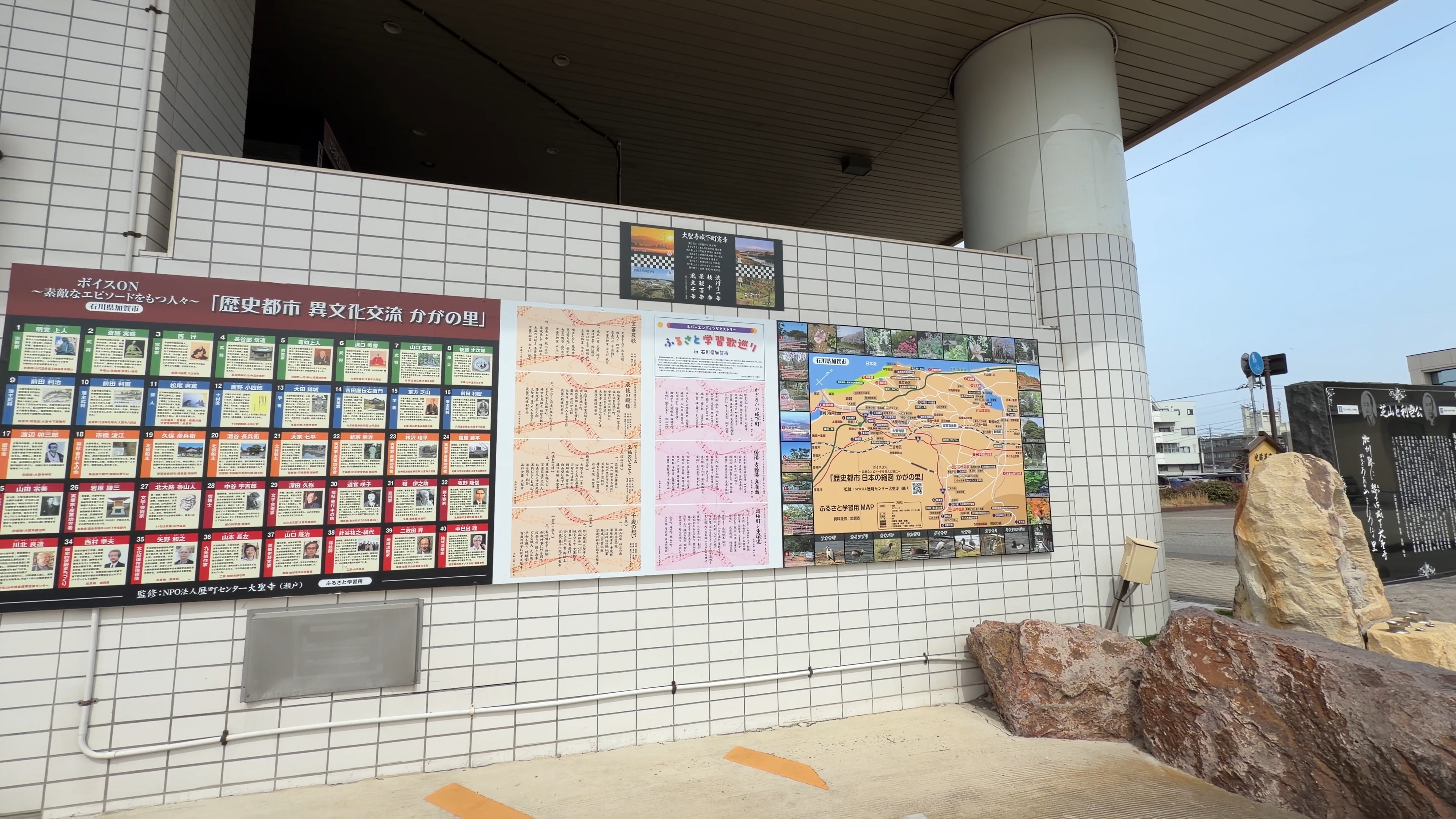 駅の壁面に並ぶ「歴史都市 異文化交流 かがの里」の案内パネル群、ふるさと学習用マップも