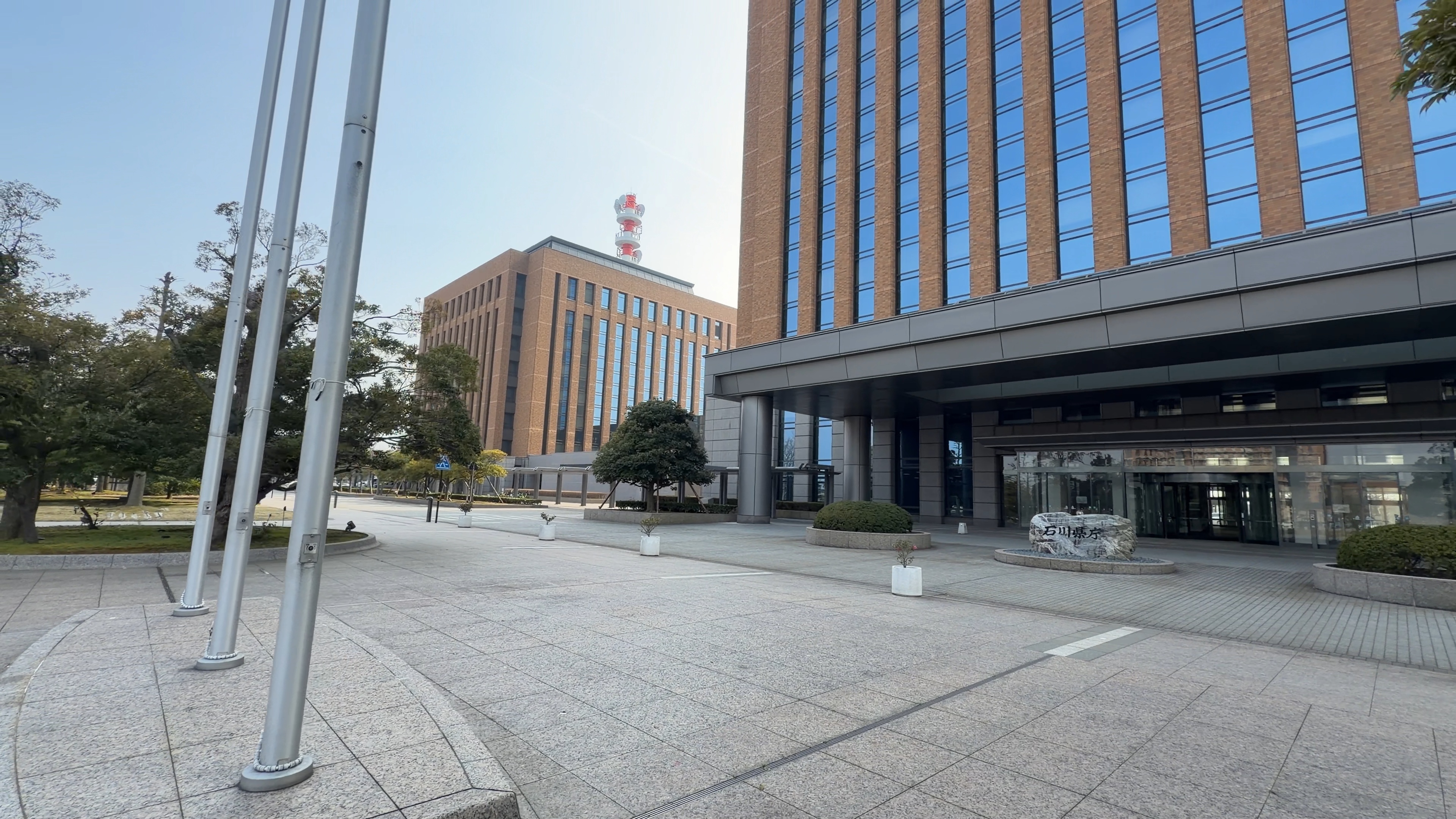 石川県庁の石碑と、奥に見える鉄塔つきの警察本部庁舎