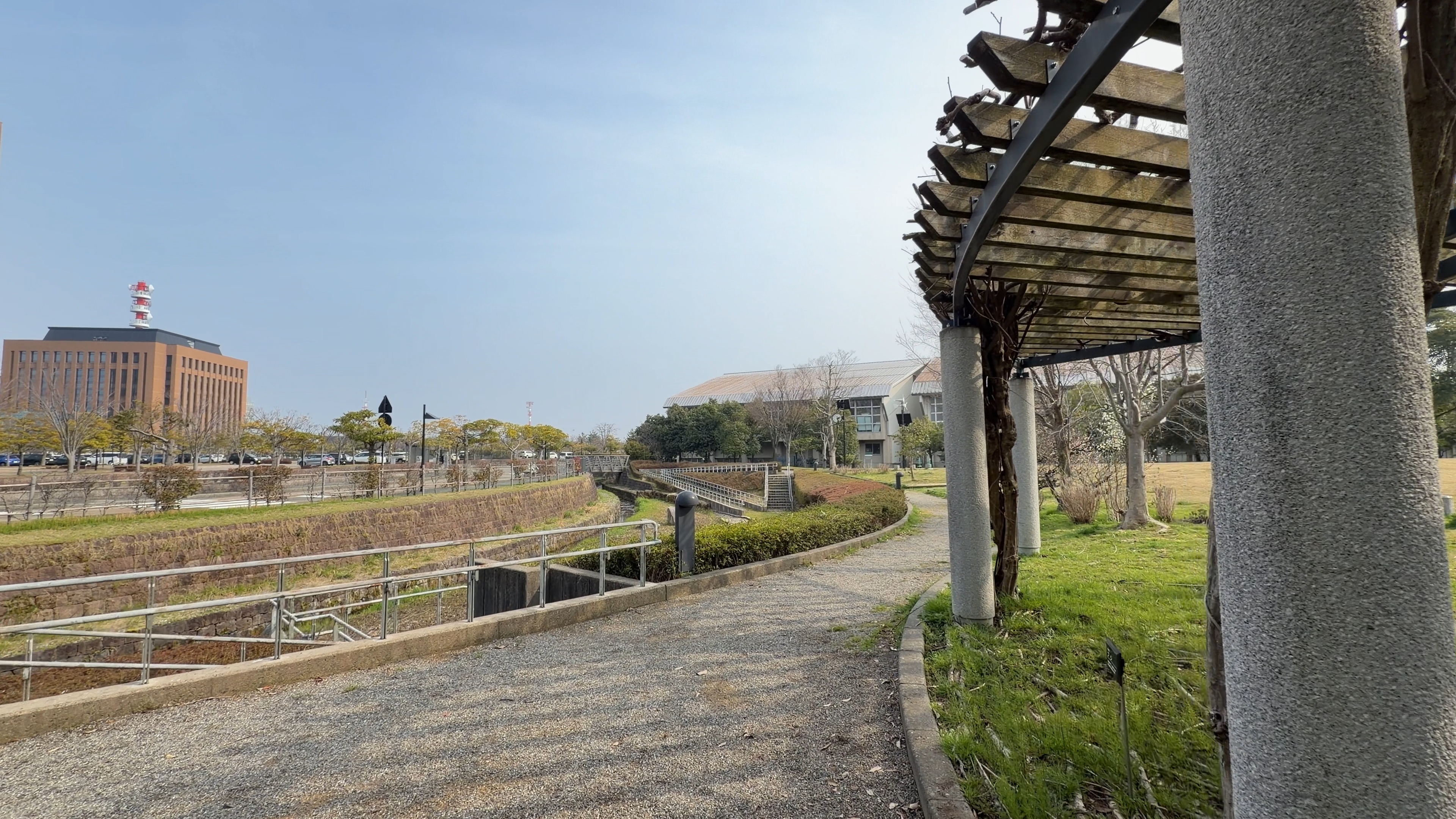 藤棚のパーゴラごしに水辺と石川県庁舎を望む