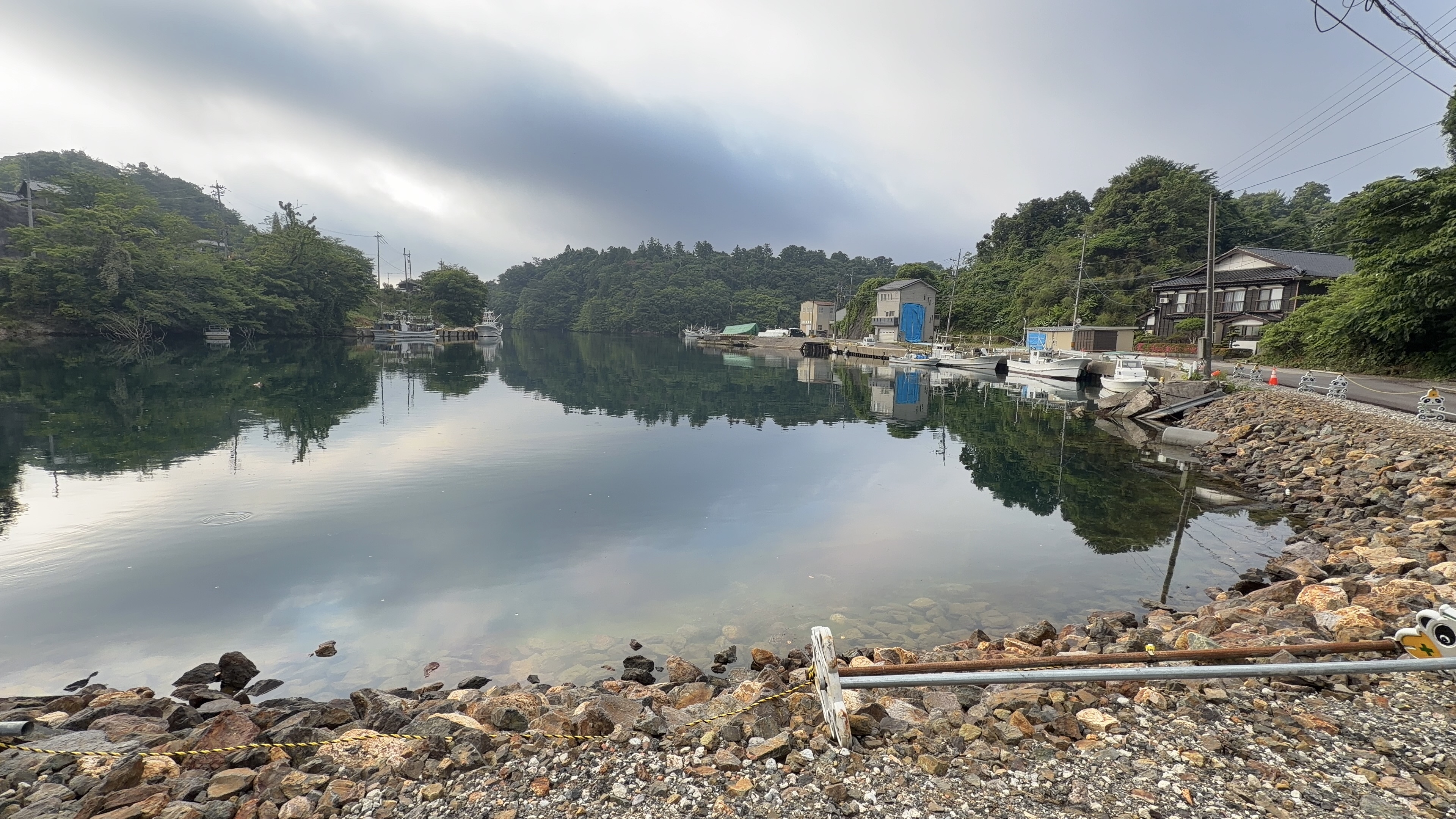 湾沿いの新しい道から見る石の岸辺と穏やかな水面
