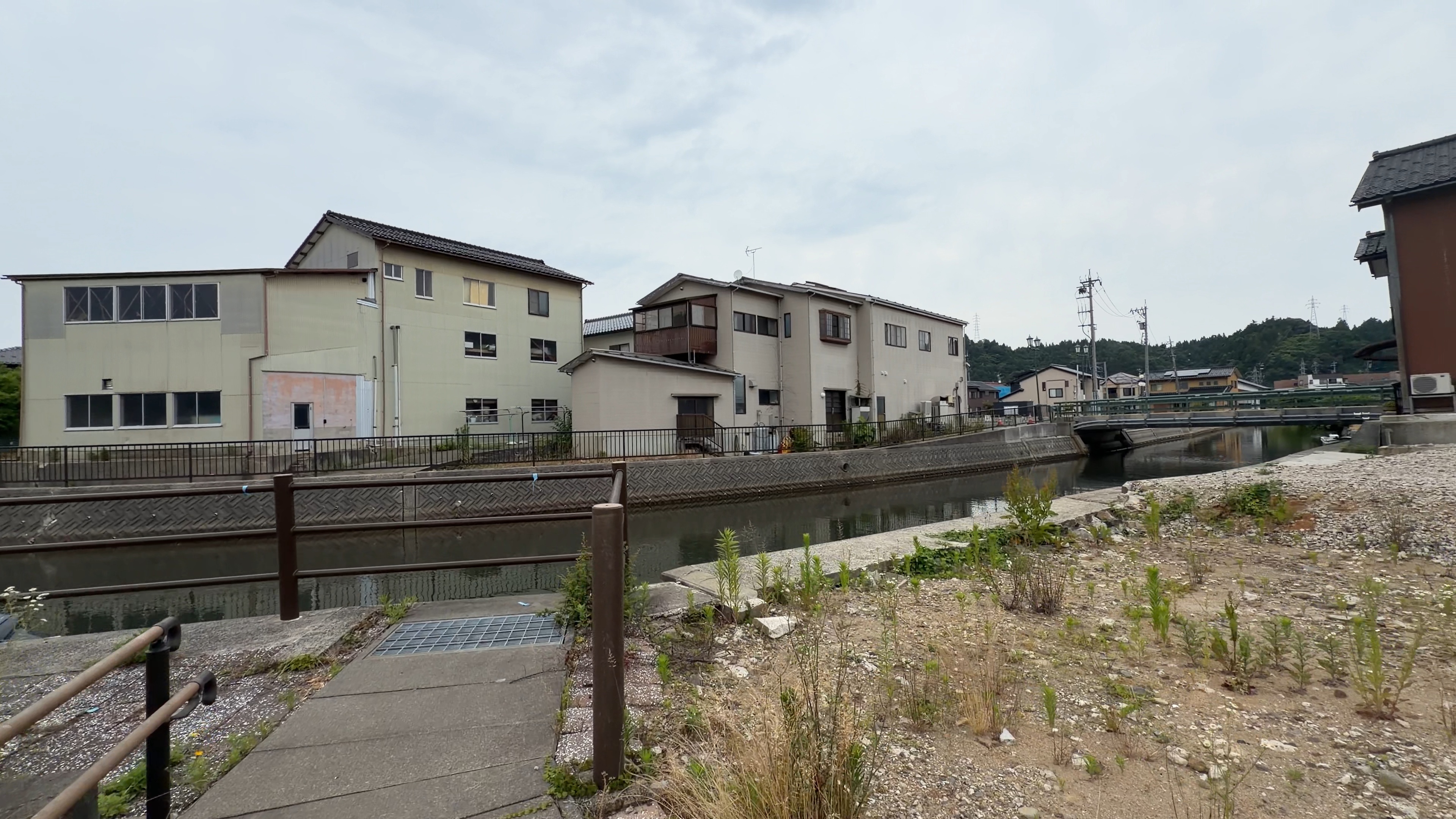 住宅の並ぶ川沿い、橋が奥に見える