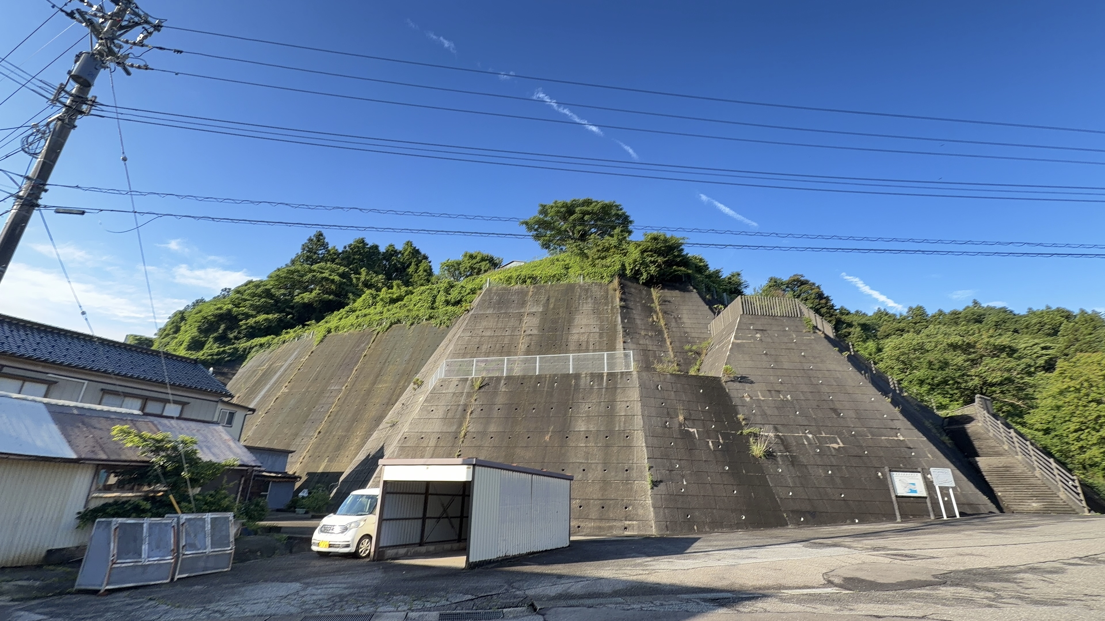 巨大な擁壁の上に伸びる飛行機雲