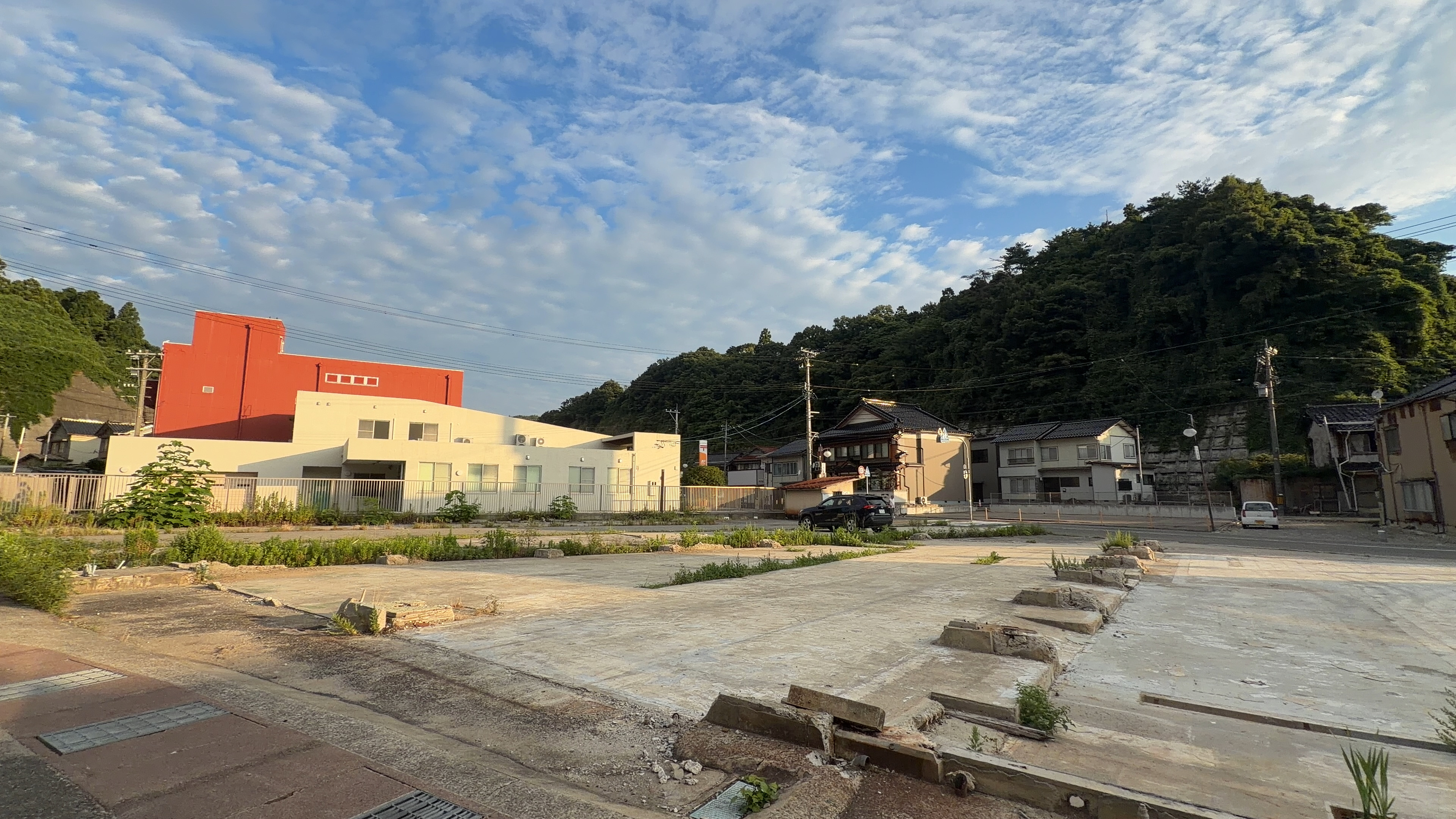 更地のまま残る空き地と、オレンジ色の壁の建物