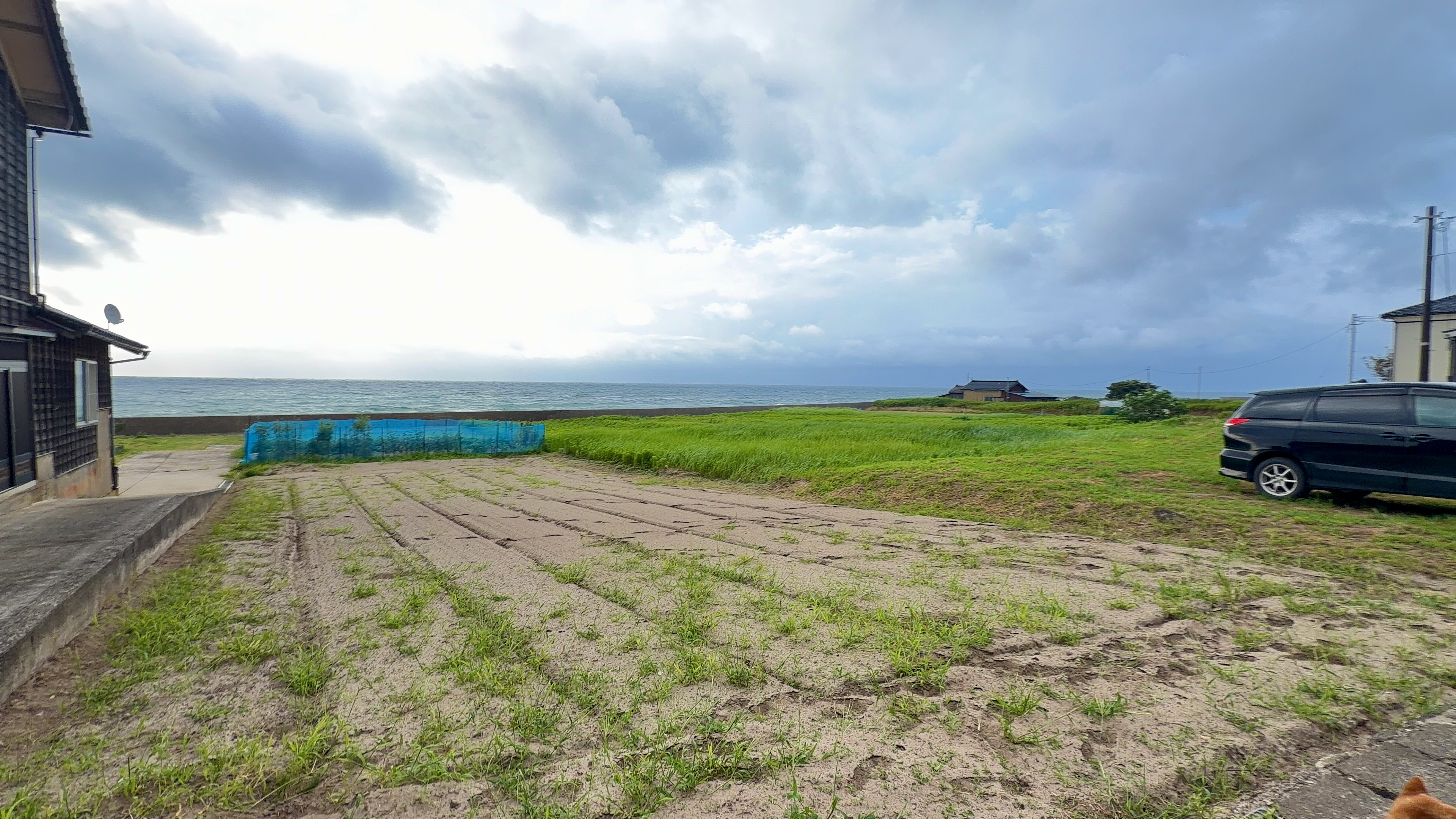 住宅のそばの空き地と、その先に見える海