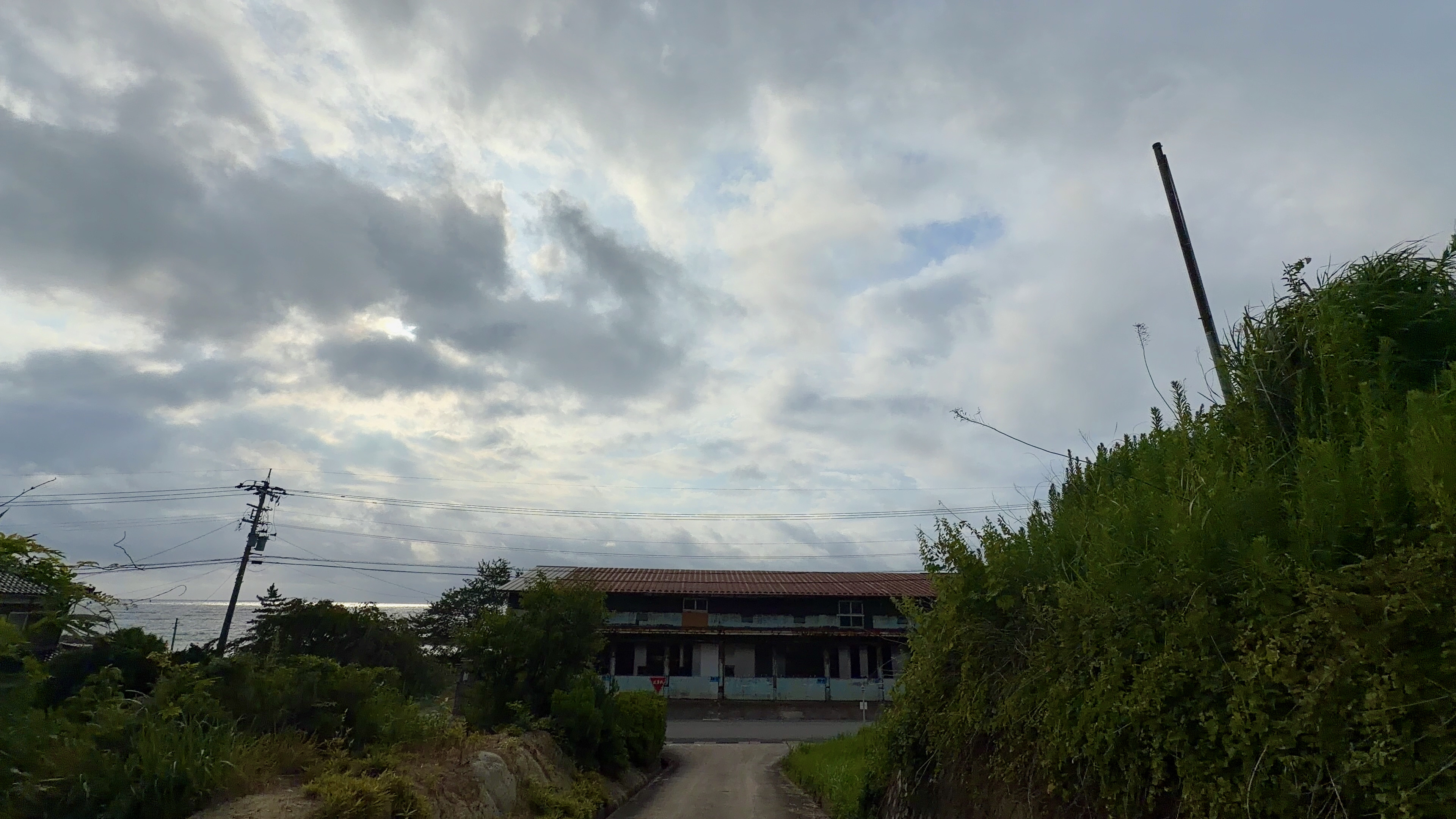 坂道の先、大きな建物の向こうに光る海
