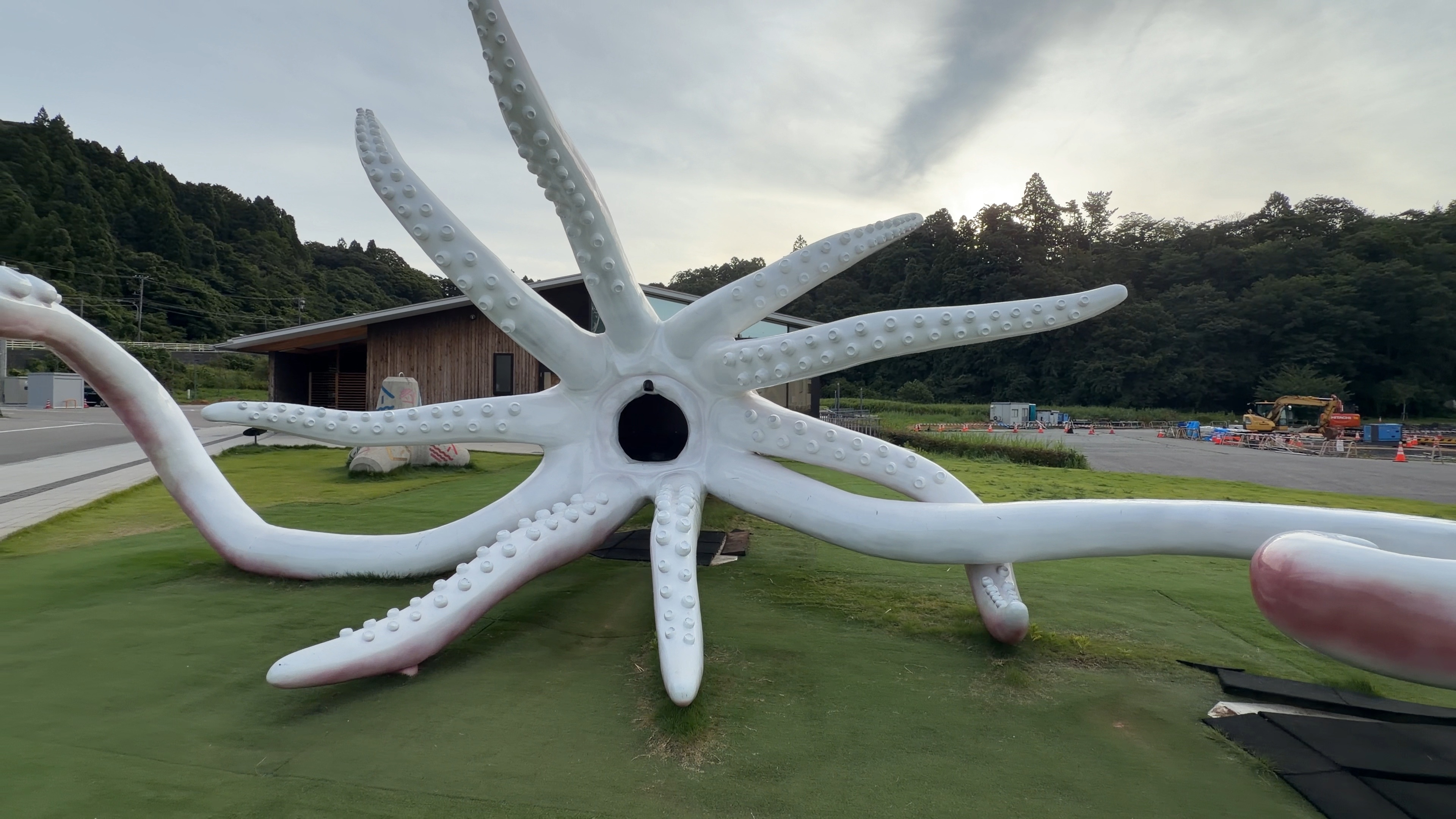 足を大きく広げたイカのモニュメント「イカキング」、朝焼けの空を背に
