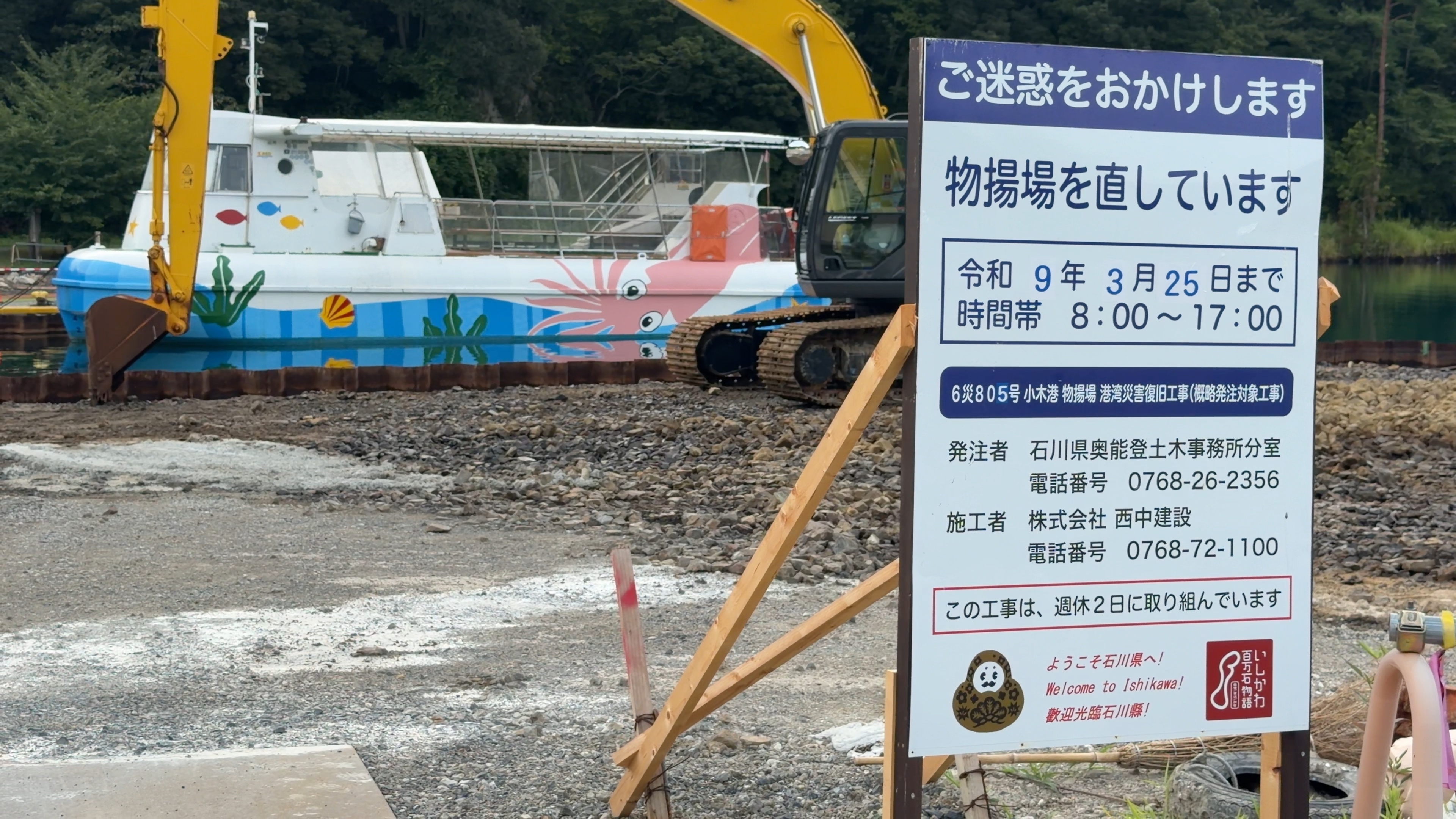 重機とクレーン船が入った物揚場の復旧工事現場、看板には工期の記載