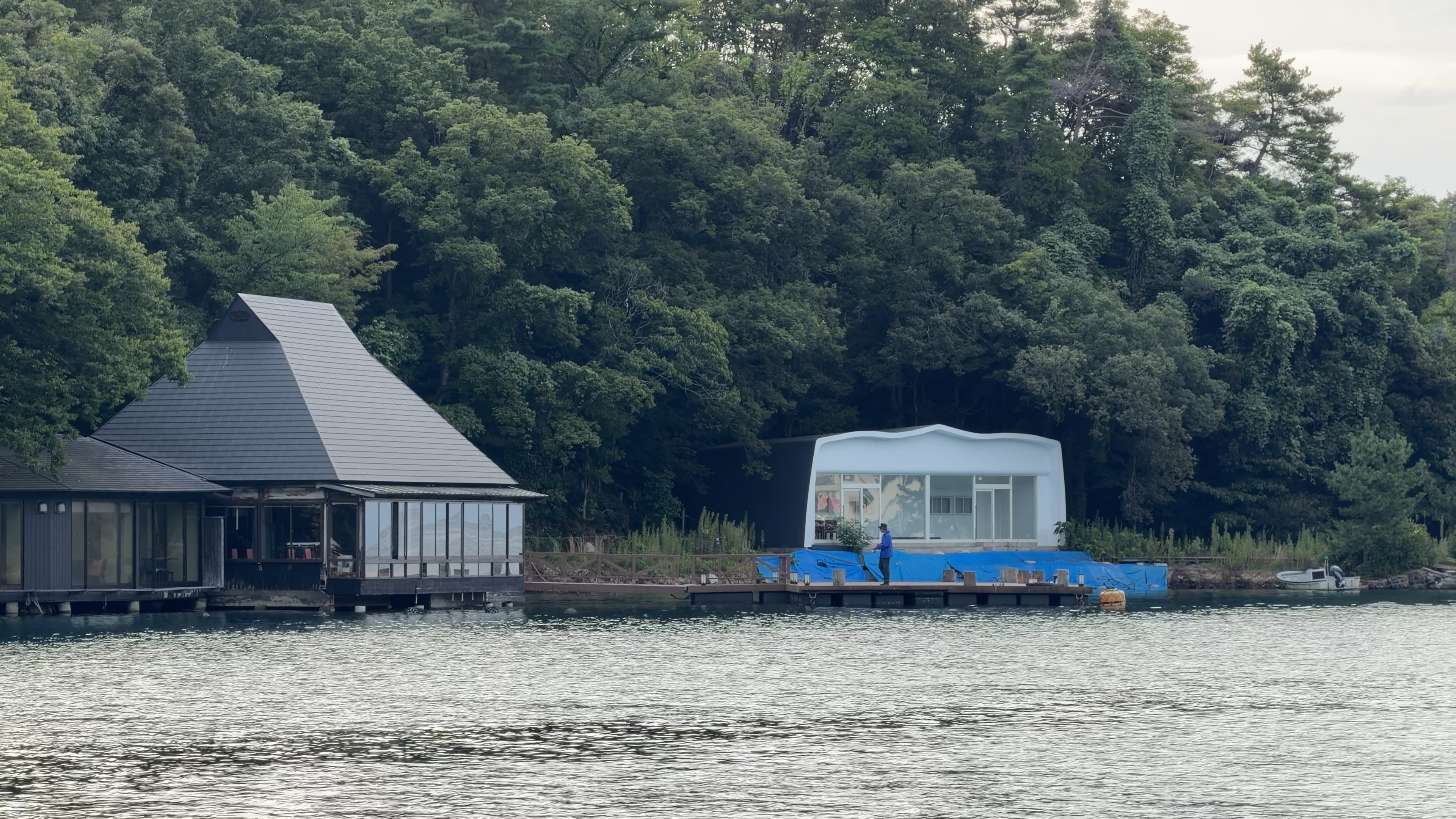百楽荘の桟橋で釣りをする人、対岸には三角屋根の建物