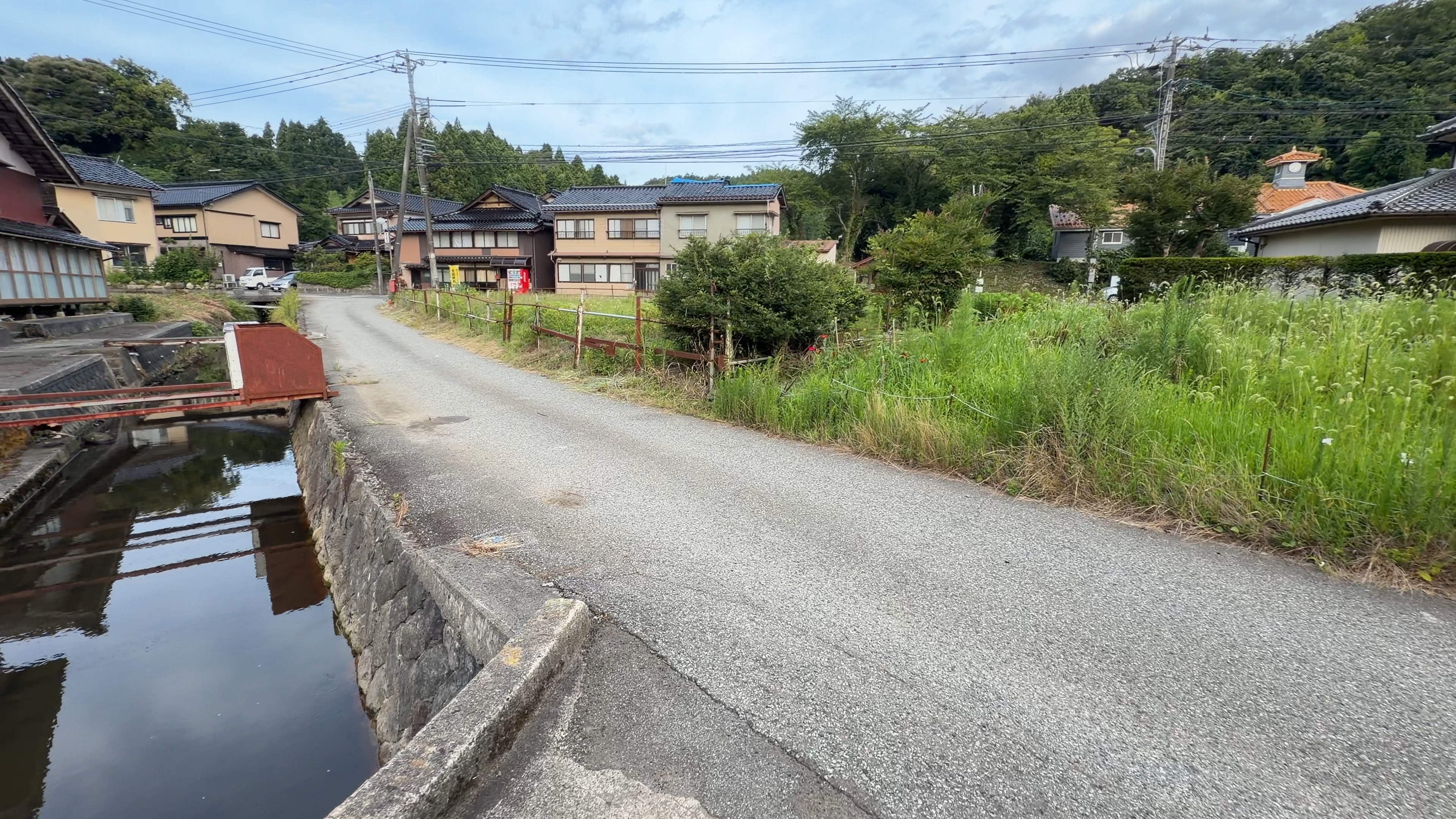 集落の水路をまたぐ赤い鉄製の小さな橋
