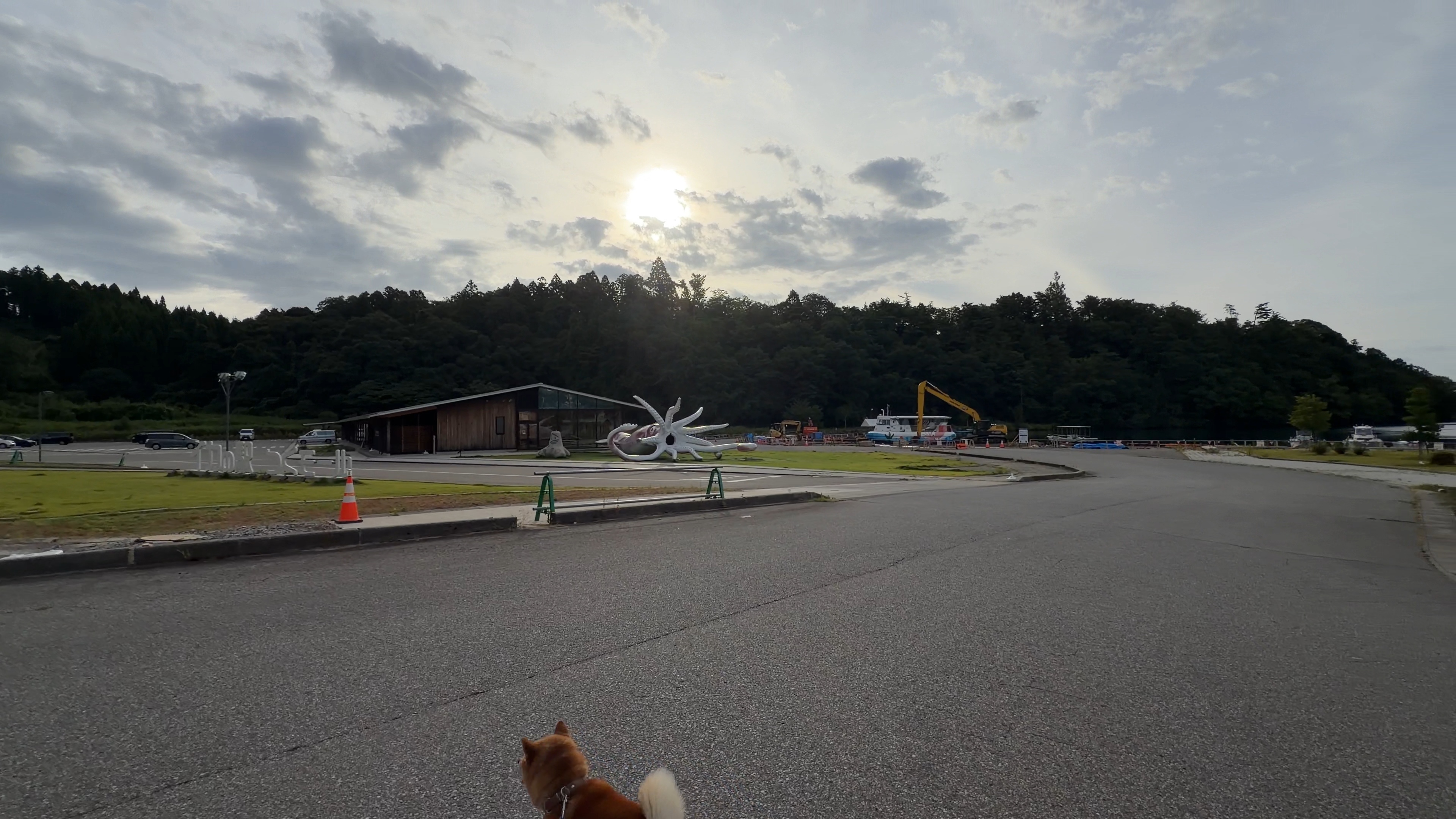 イカの駅つくモールの建物前を歩くたろーさん、ENEOSの看板が見える朝の道