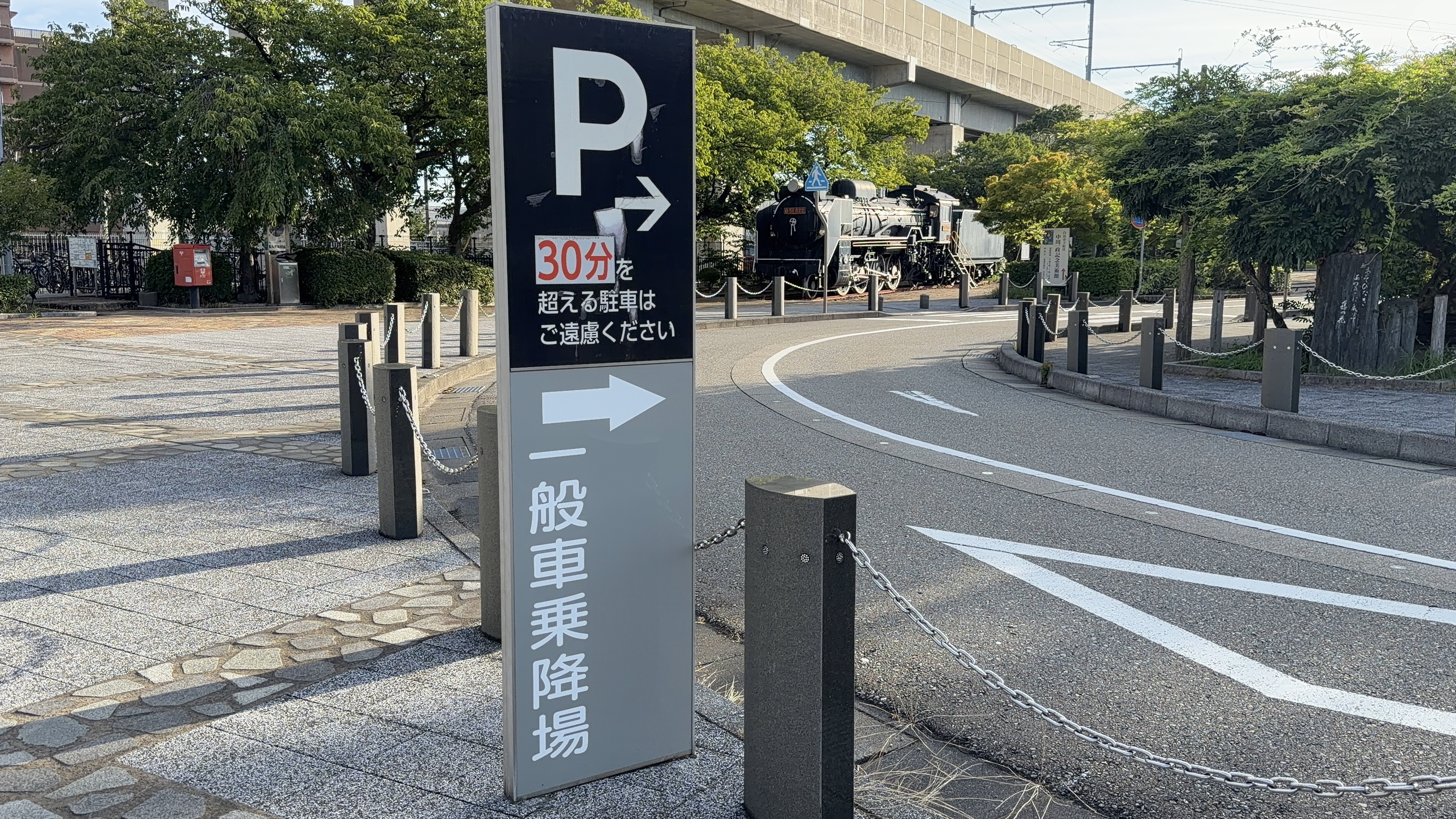 「一般車乗降場」の案内標識と、奥に見える黒い蒸気機関車D51