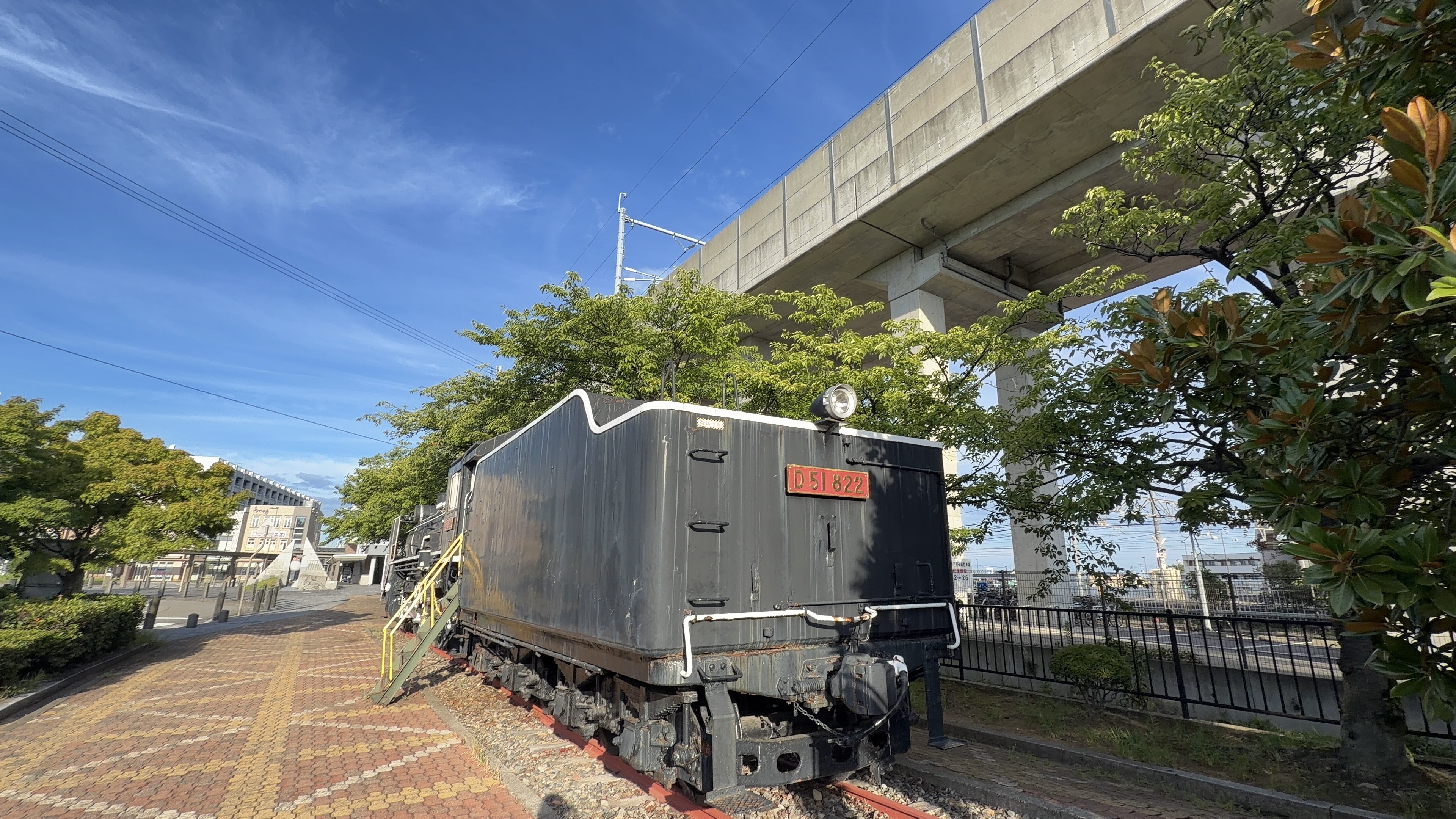 D51のうしろに連結されたテンダー、石炭を積む黒い車両、高架のむこうに市街地