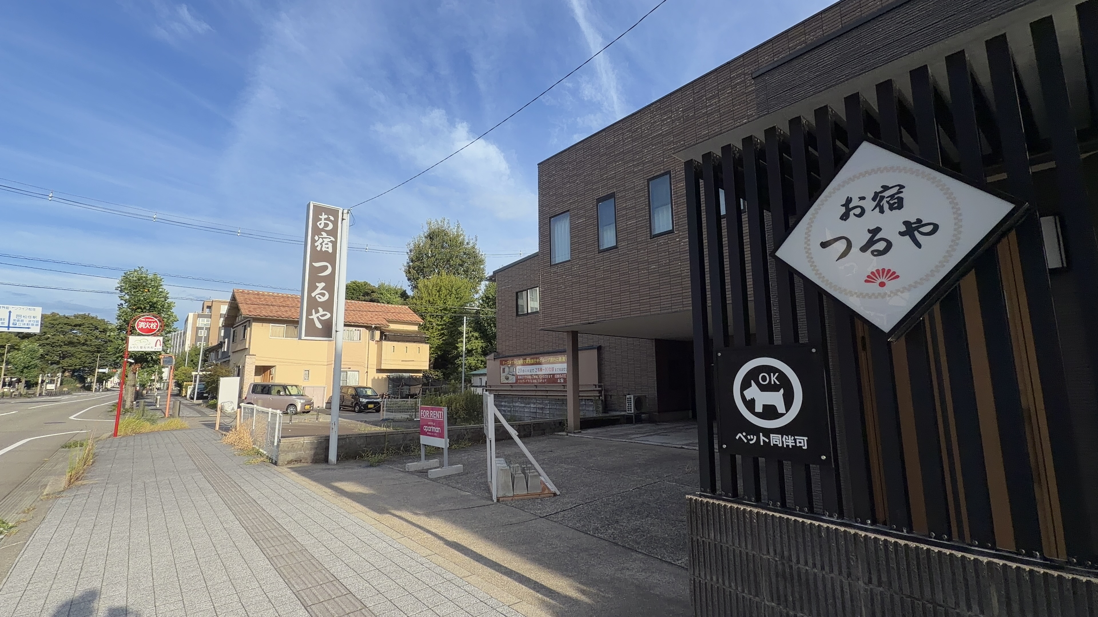 旅館「お宿 つるや」の看板、ペット同伴OKのマーク、茶色いタイルの建物