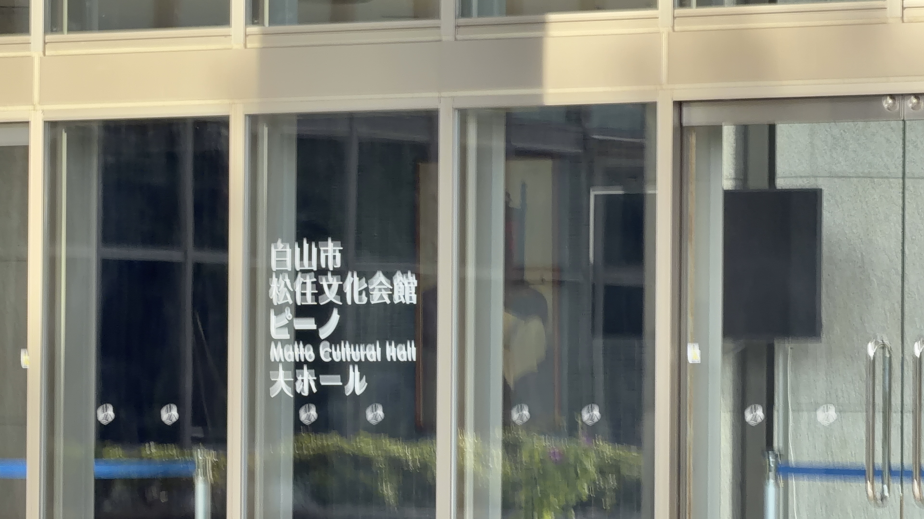 ガラス越しに見える「白山市松任文化会館ピーノ Matto Cultural Hall 大ホール」のサイン