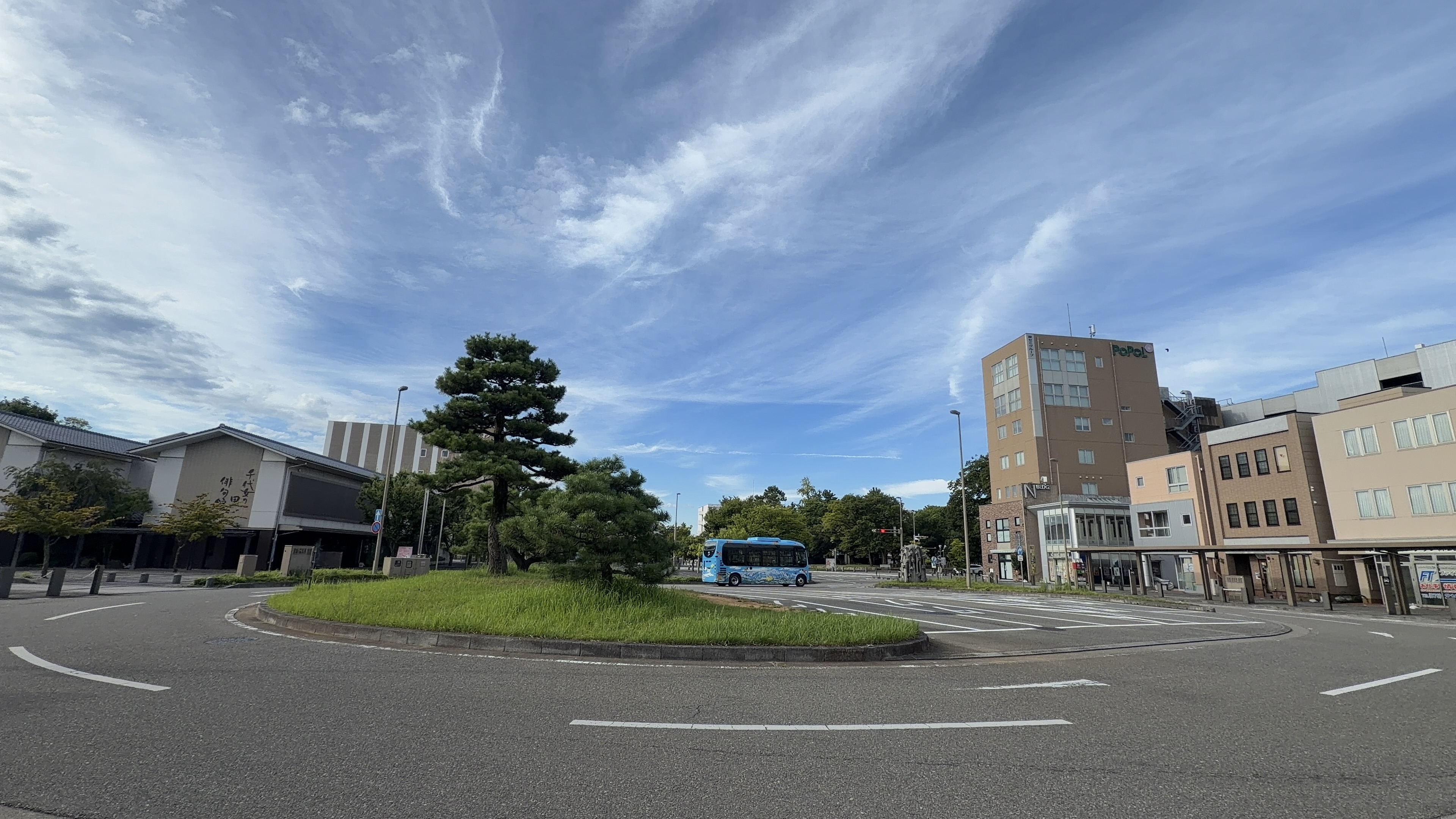 松任駅前のロータリーを別角度から見た様子、松の木とバス