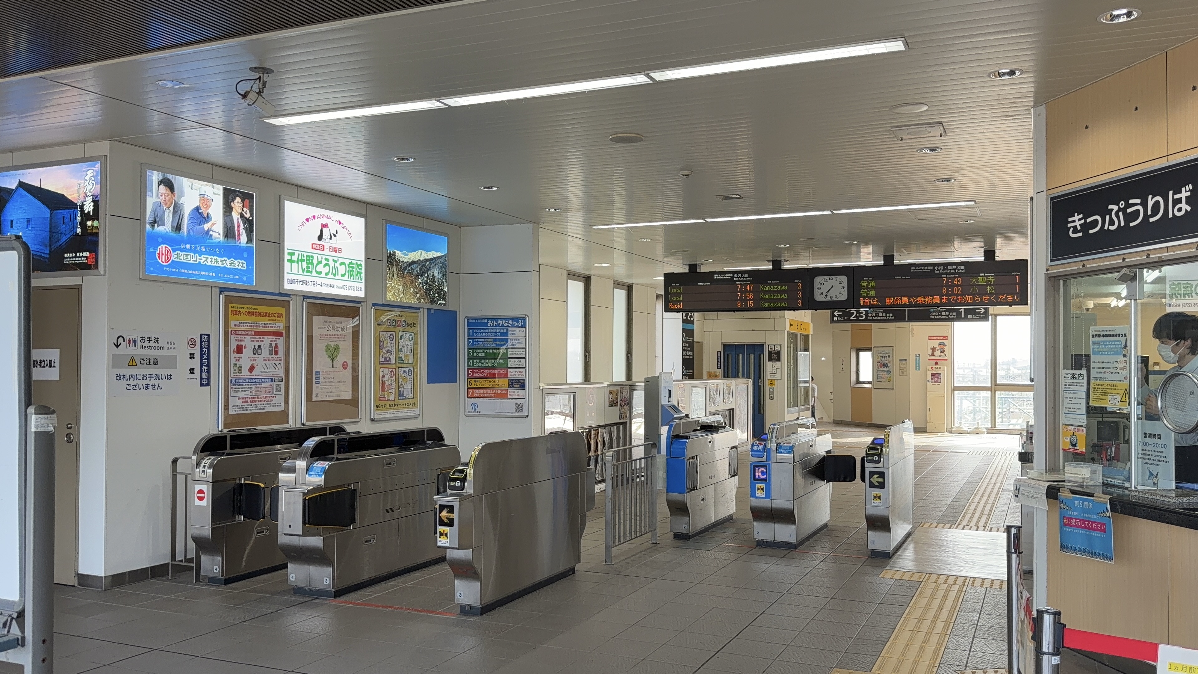 松任駅の改札口、自動改札機と発車標「普通 7:43 大聖寺」「普通 8:02 小松」、隣にKanazawa方面の発車標も並ぶ、きっぷうりばの窓口
