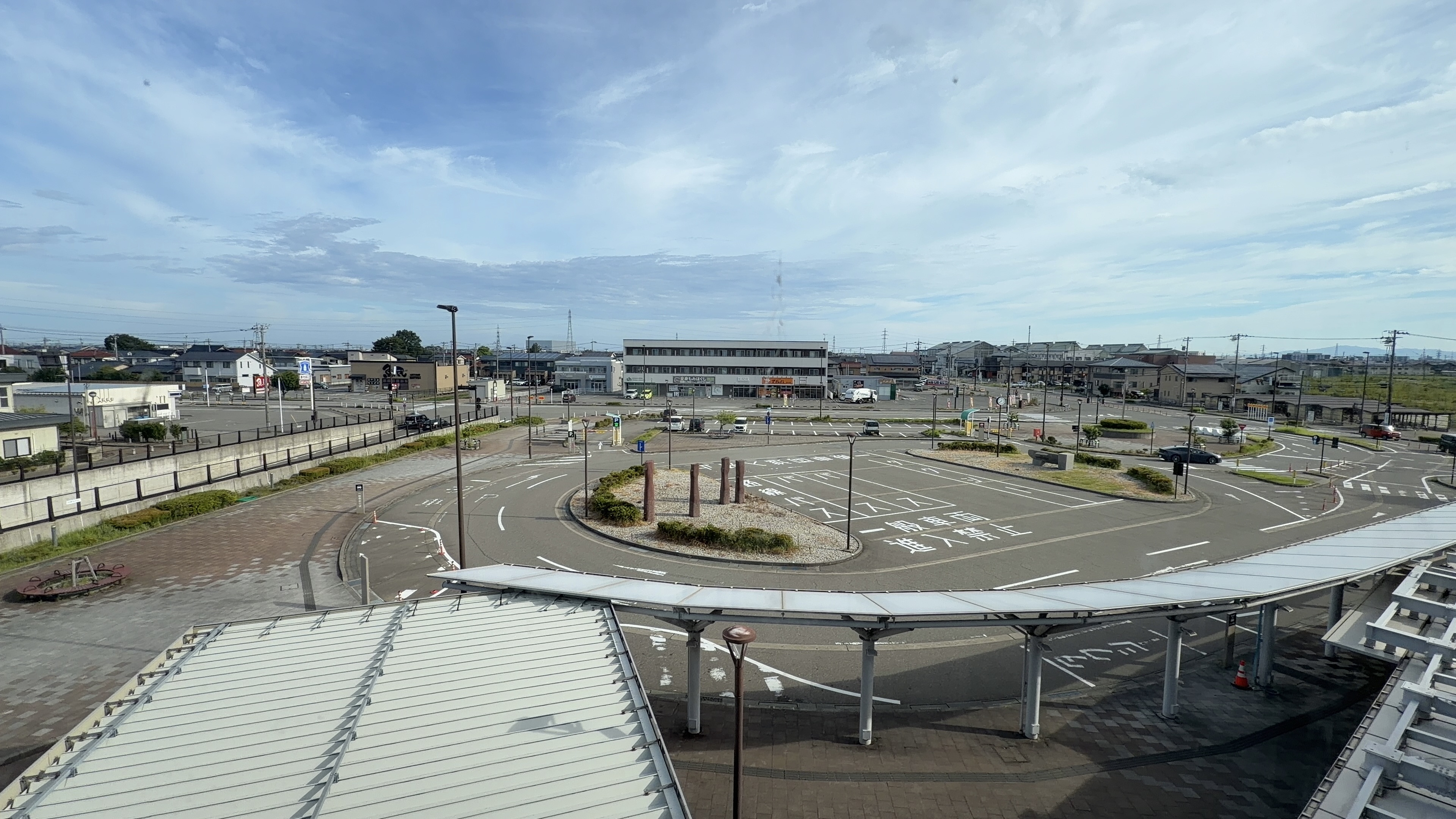 北口駅前ロータリーを見下ろす、丸い緑地帯と周囲の道路、奥の商業ビル