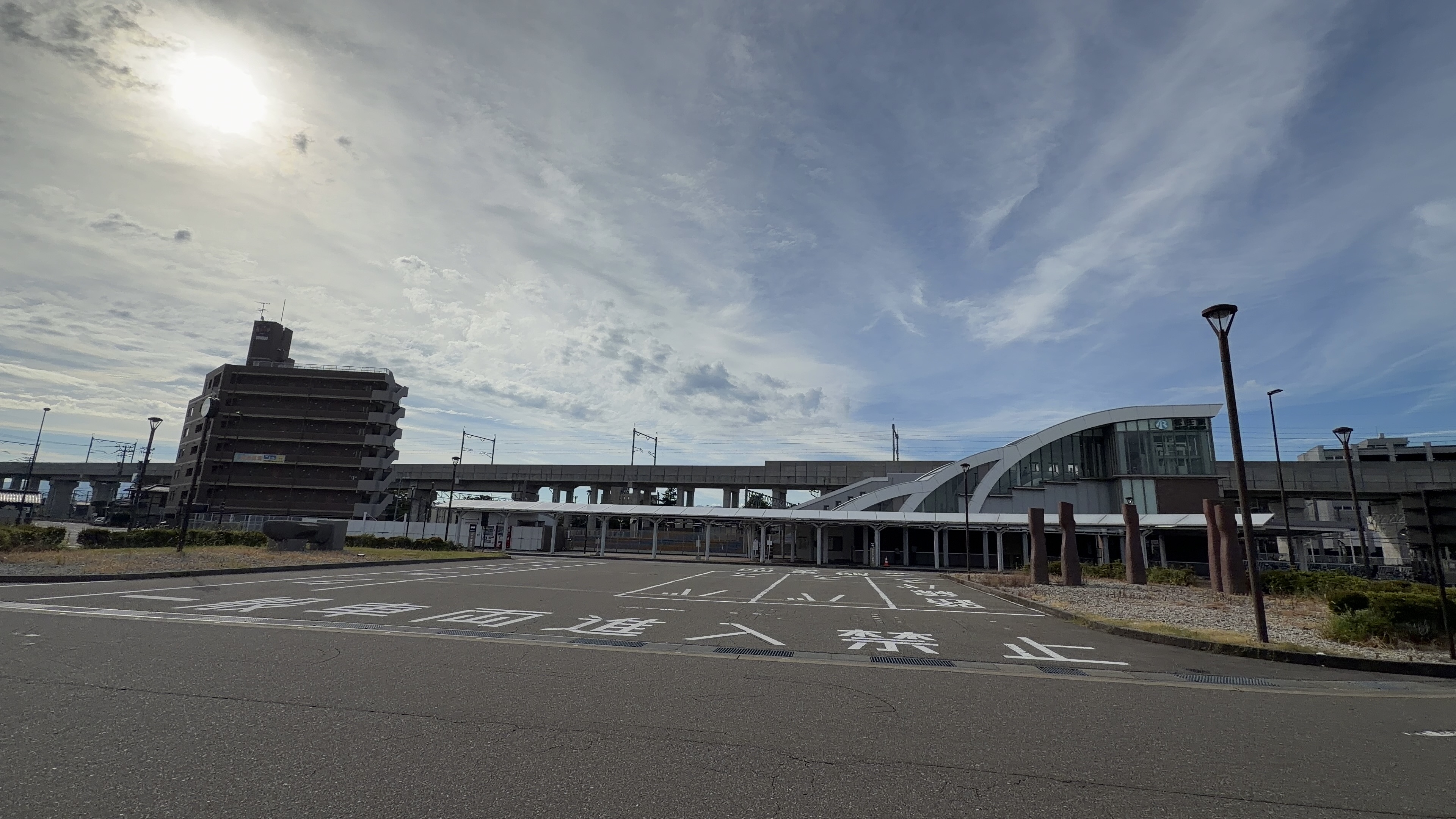 道路に書かれた「一般車両進入禁止」の文字の奥に見える松任駅、白いアーチ屋根と時計塔