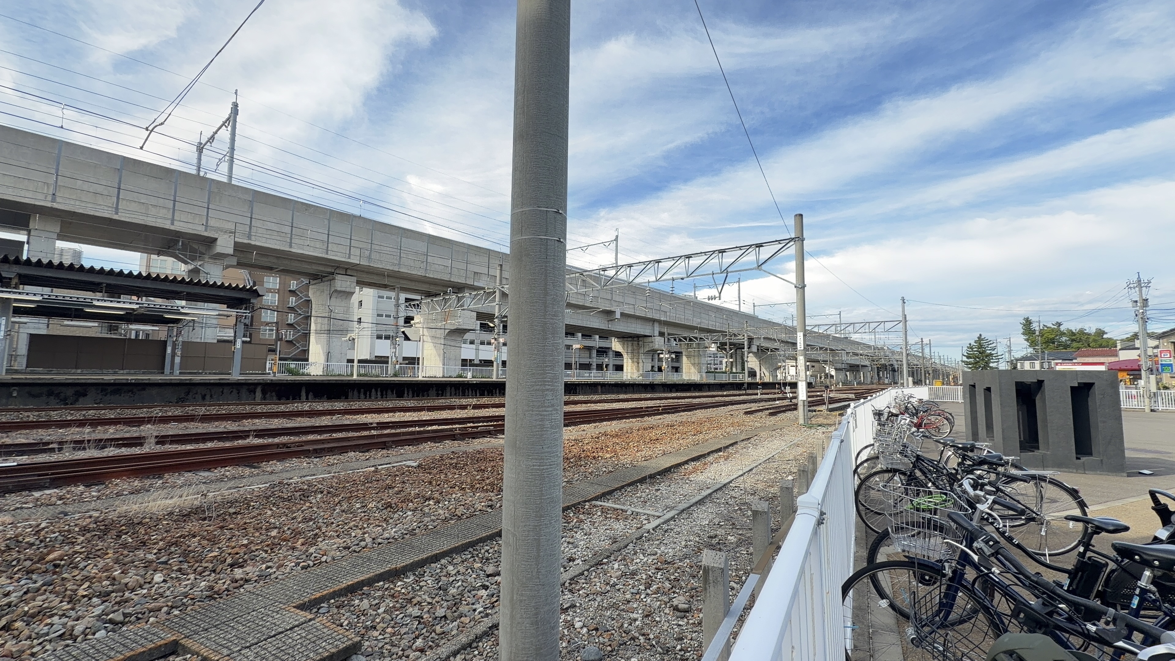 駅そばの駐輪場に並ぶ自転車、線路と高架橋の眺め