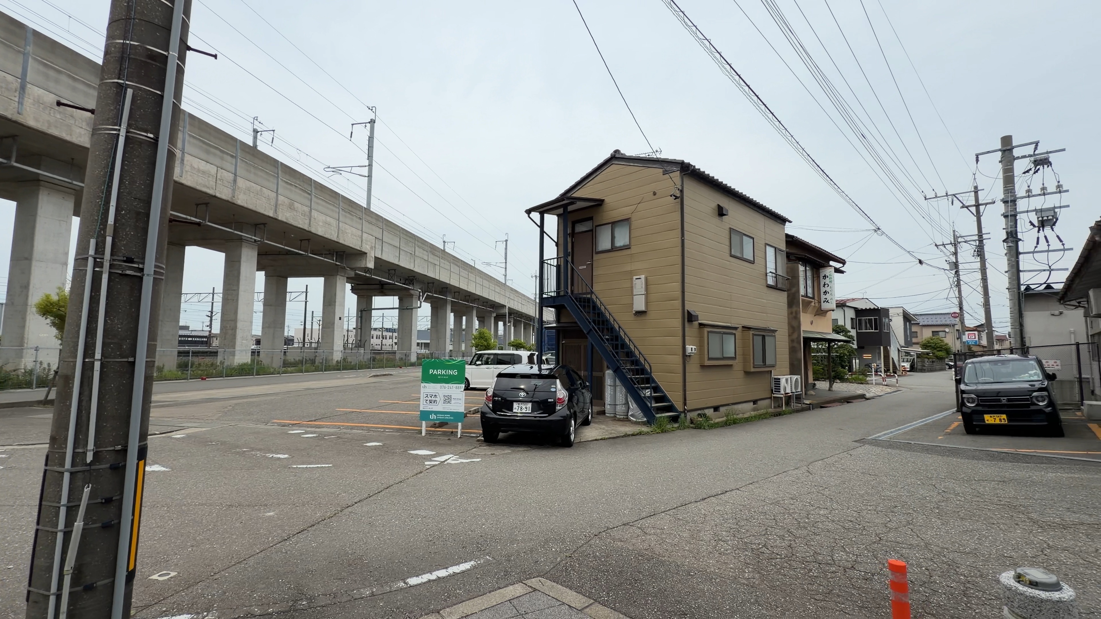 高架の下に伸びる駐車場と歩道、奥にIRいしかわ鉄道の高架橋