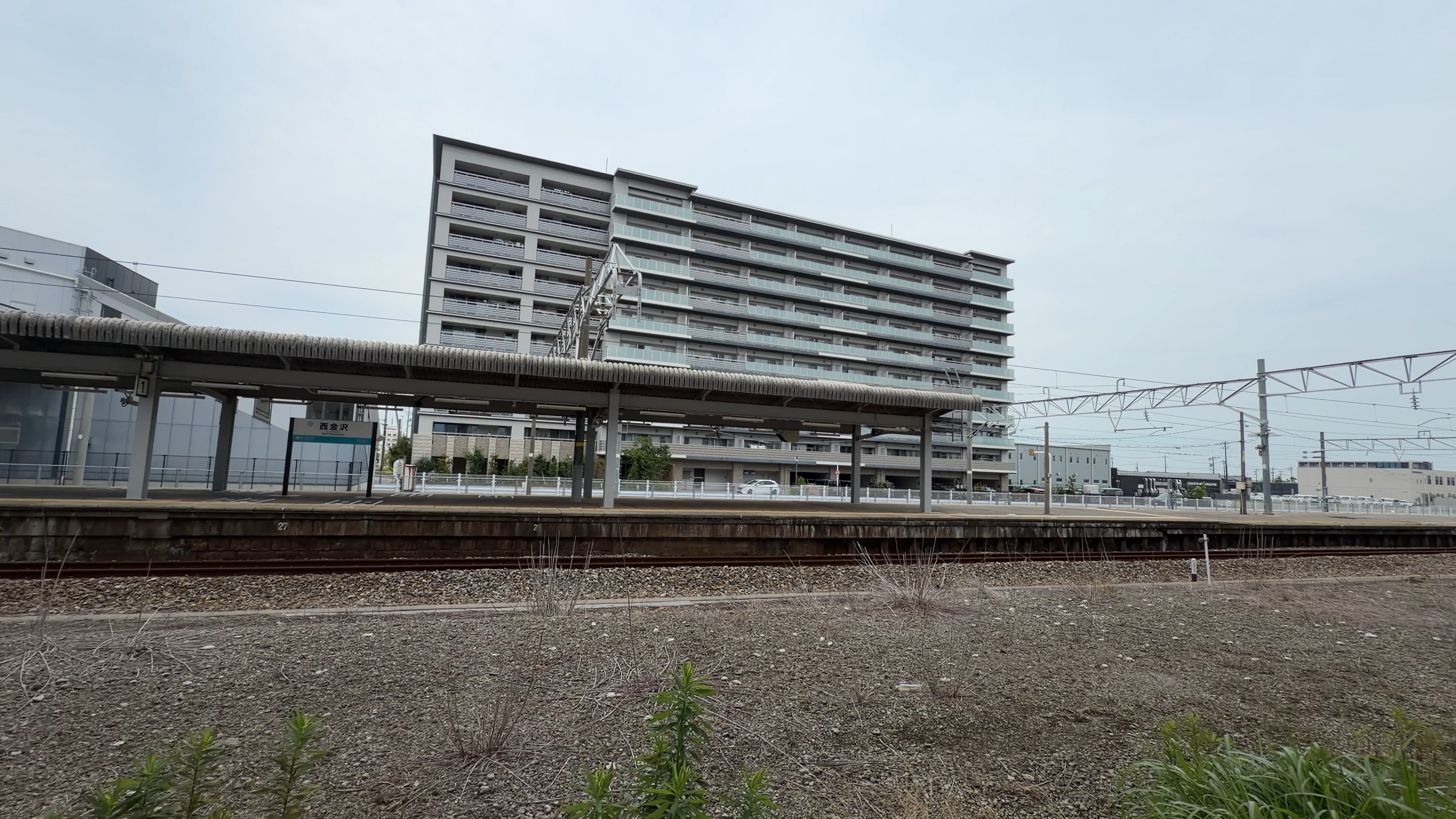 西金沢駅のホーム、「西金沢」の駅名標と背後の高層マンション