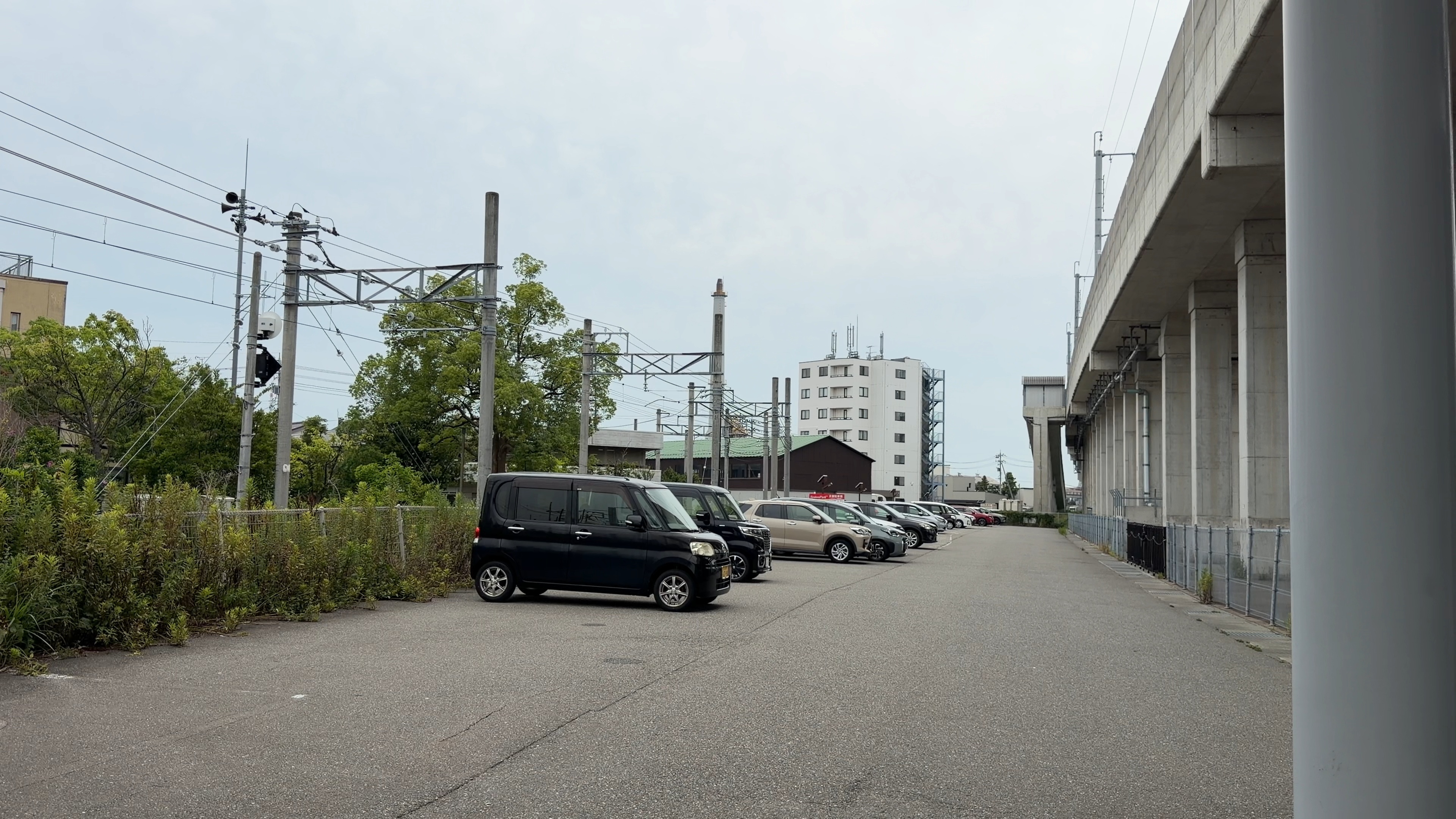 西金沢駅の送迎用駐車場、奥に高架橋と駐車中の車列