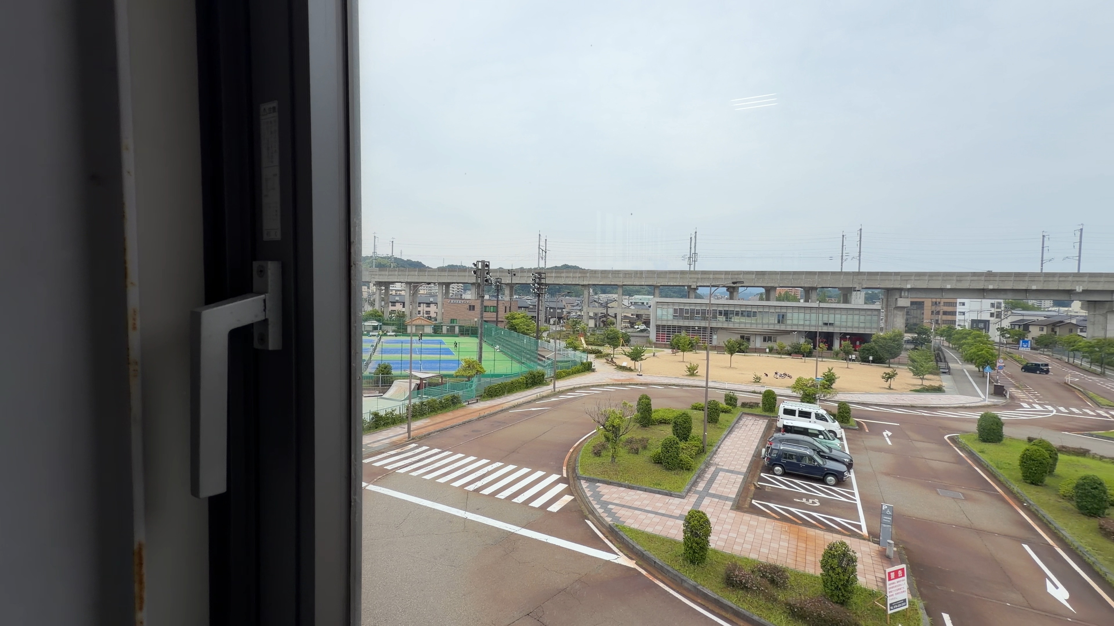 通路の窓から見える駅前ロータリーとテニスコート、新幹線高架