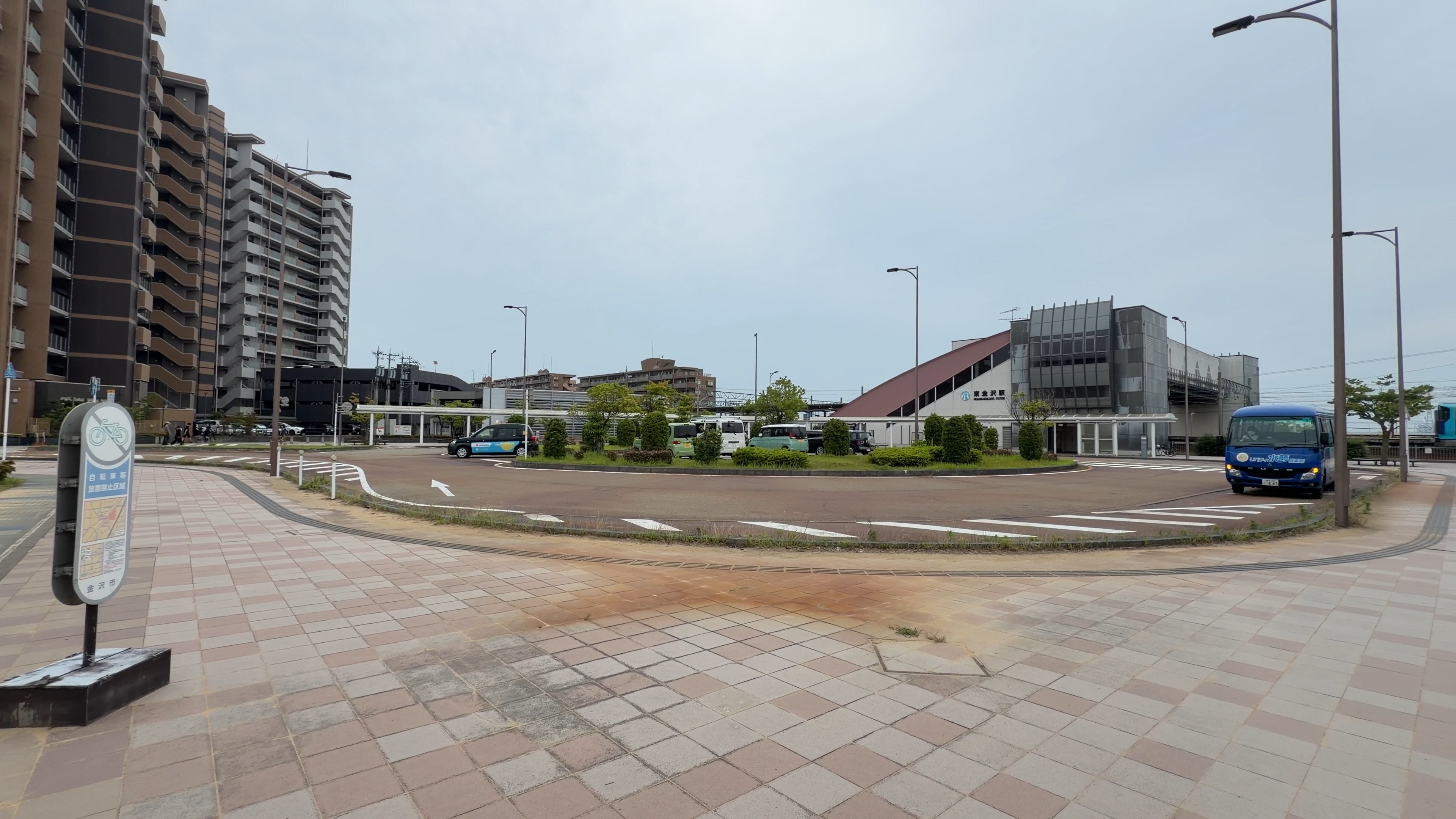 東金沢駅前のロータリーに停まる路線バス、背後に高層マンションと駅舎